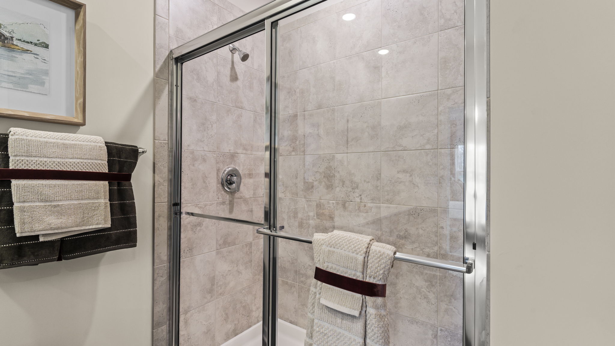 Closeup of quartz walk-in shower with gray, white, and red towels.