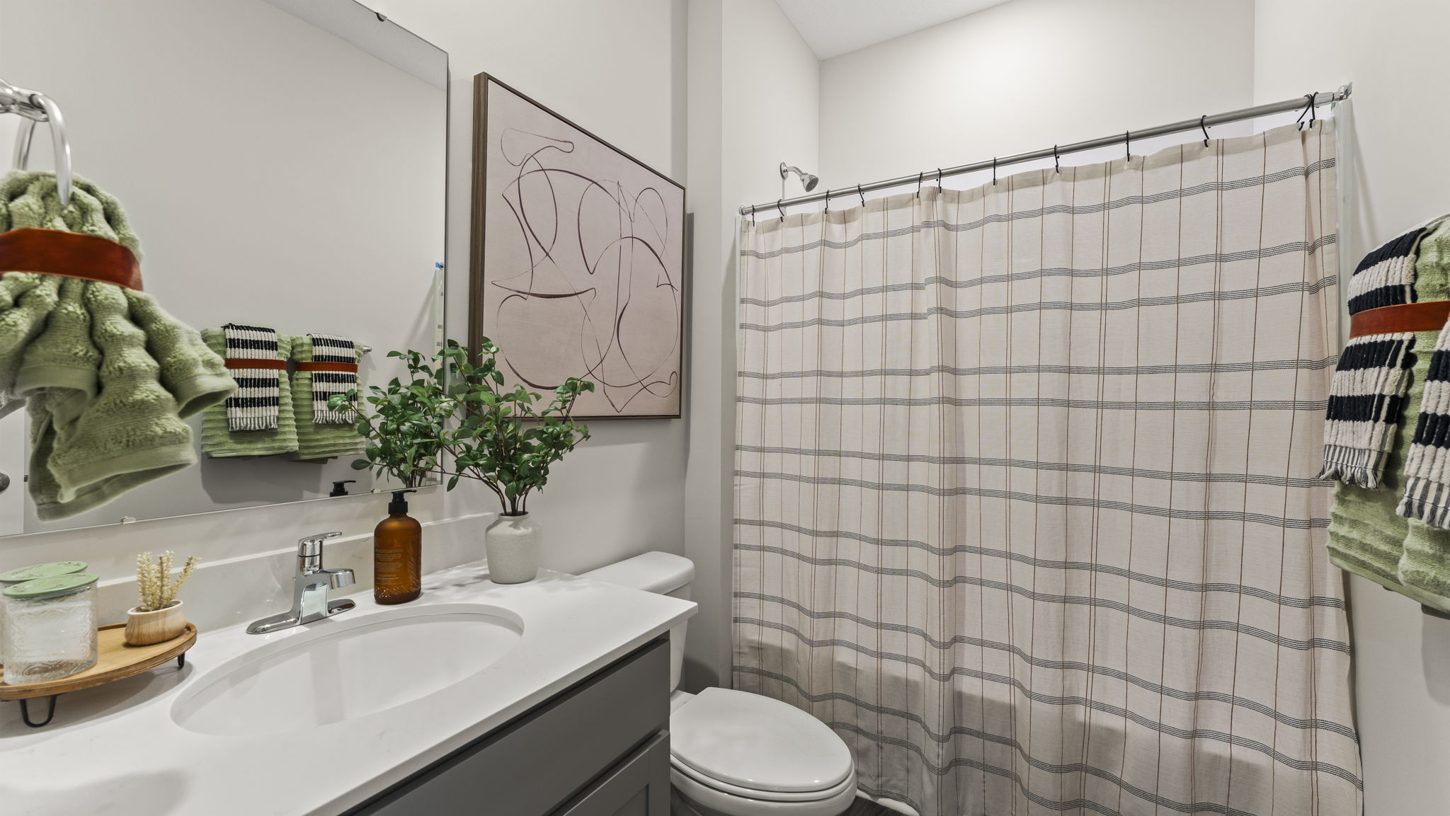 Bathroom with green and brown cloths and sink with mirror.