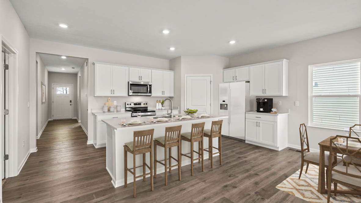 Open Concept kitchen with white cabinets and stainless steel appliances with hallway to front door.