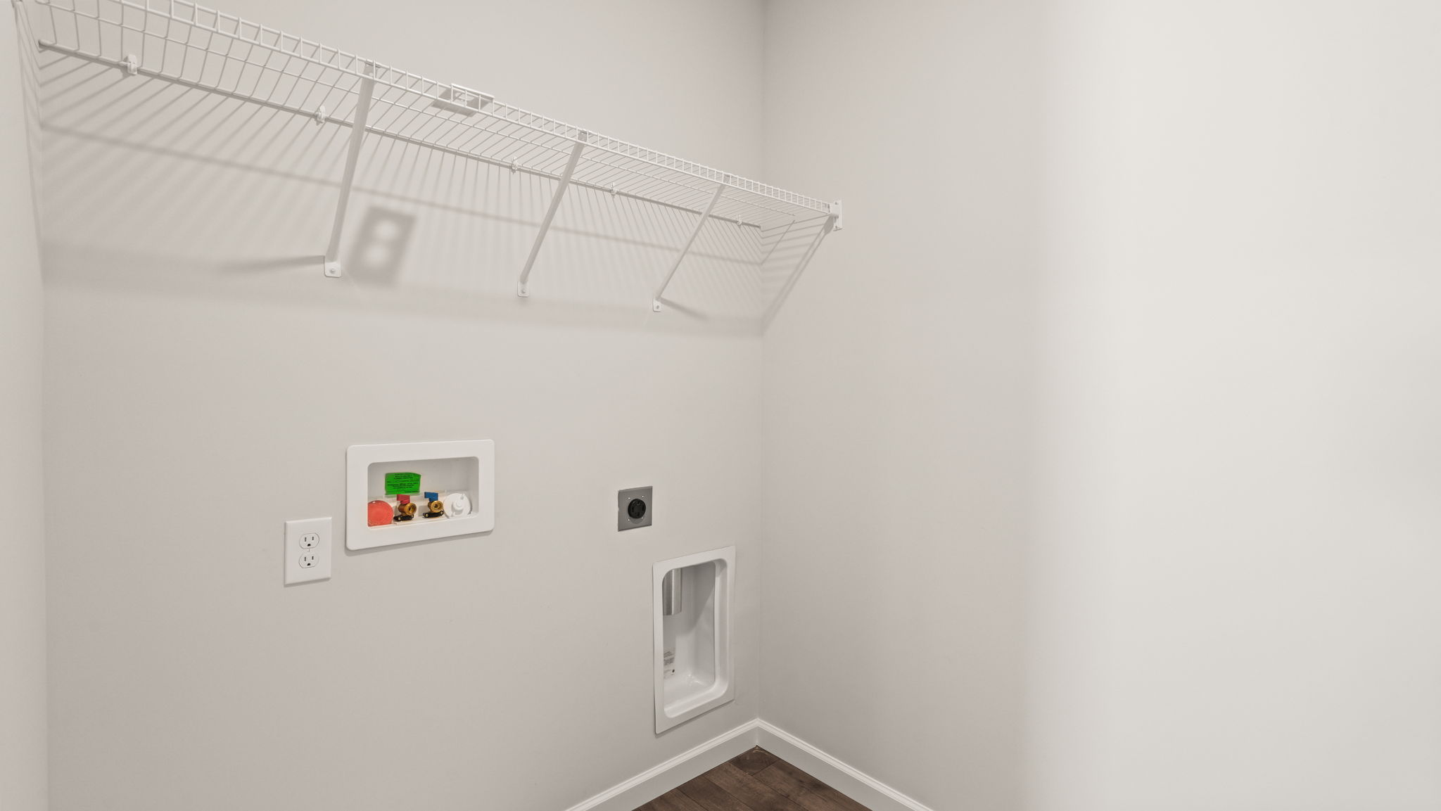 Laundry area with washer/dryer inlets and wire rack shelving.