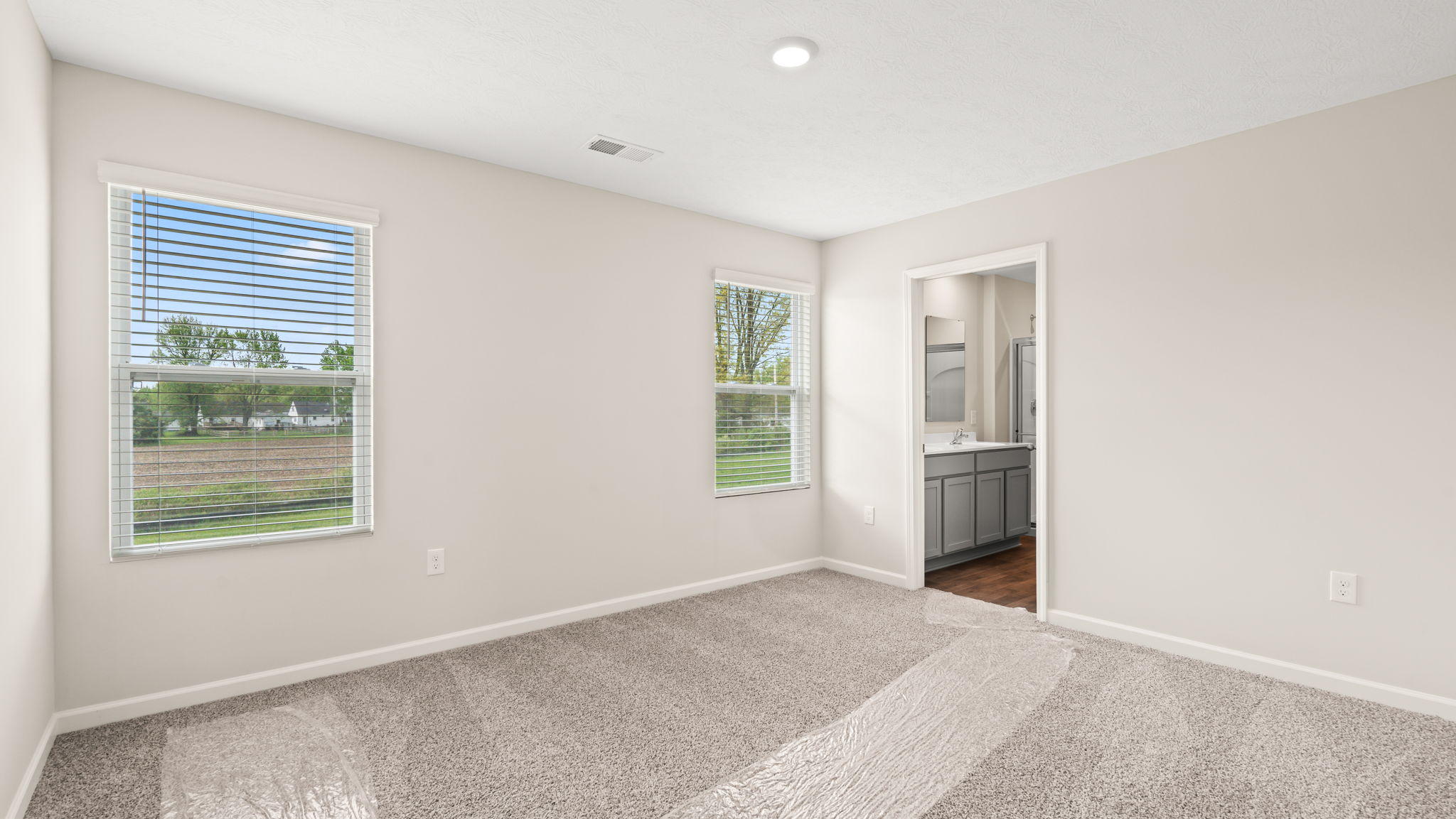 Primary bedroom with window and door to primary bathroom