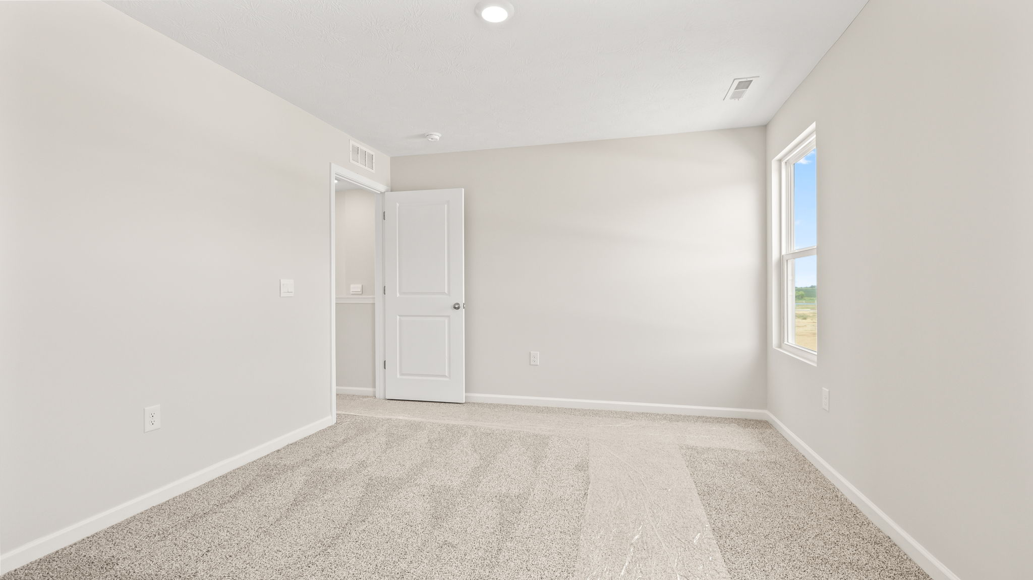 Carpeted primary bedroom with window and door to exterior