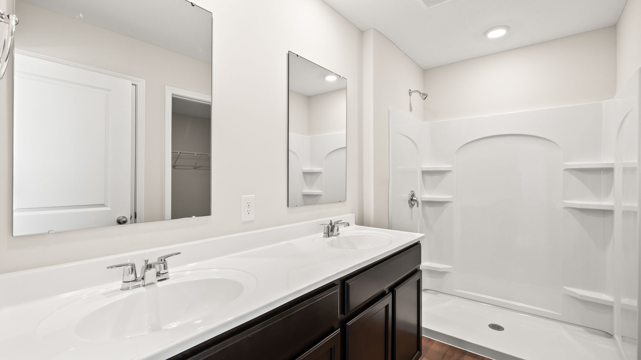 Full primary bathroom suite with double bowl sinks, mirrors, and walk-in shower