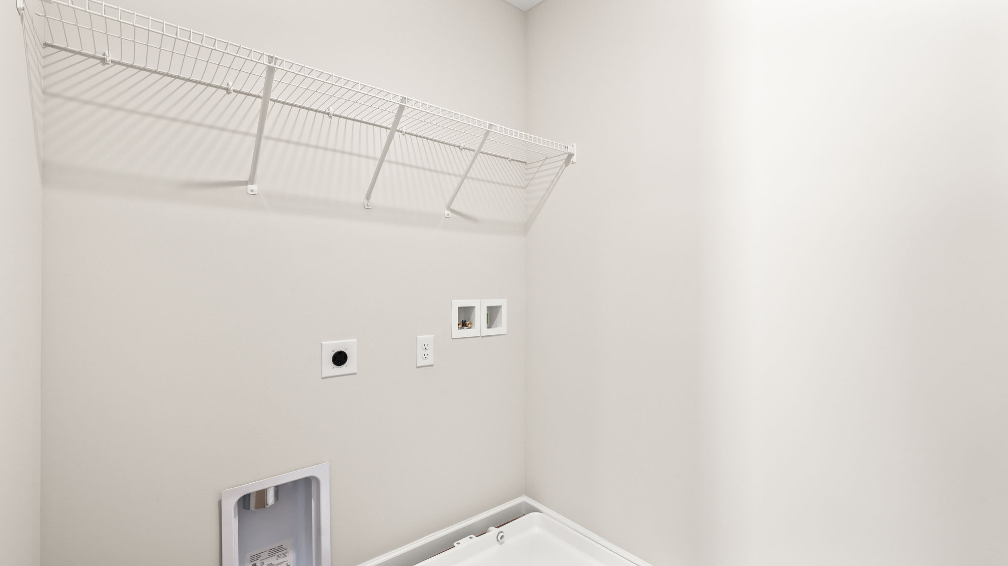 Laundry area with wire rack shelving and washer/dryer inlets