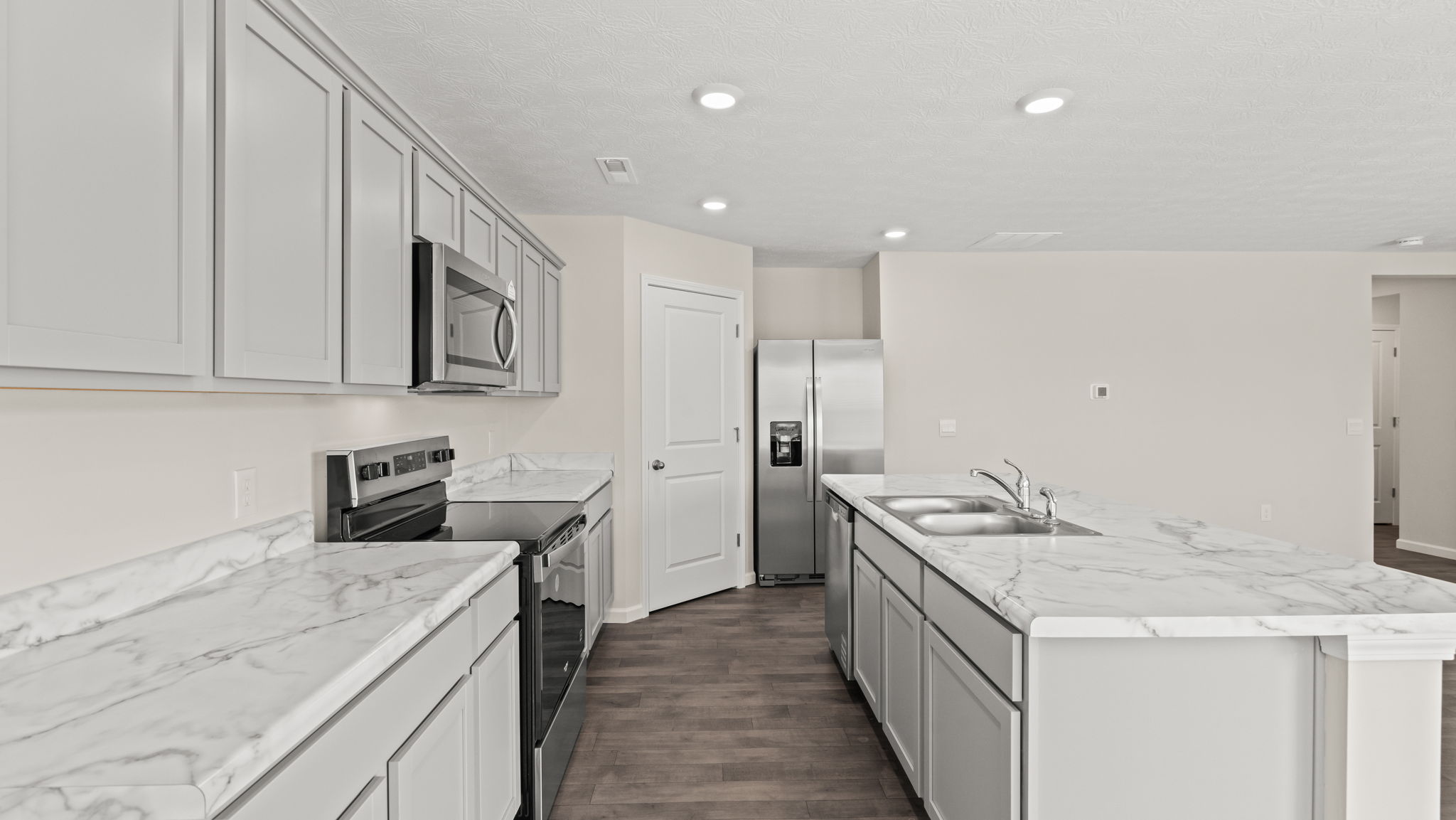 Side view of kitchen with oven range on the left, pantry in the center, and island on the right