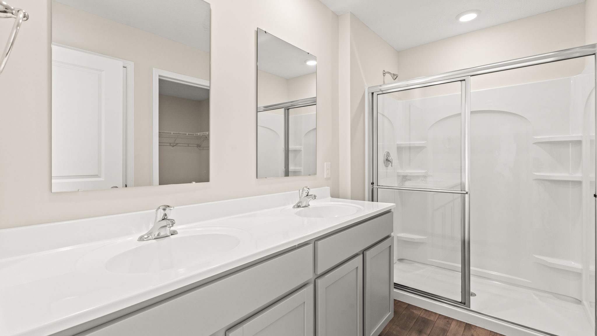 Full bathroom with dual sink and mirror vanities and glass sliding door shower