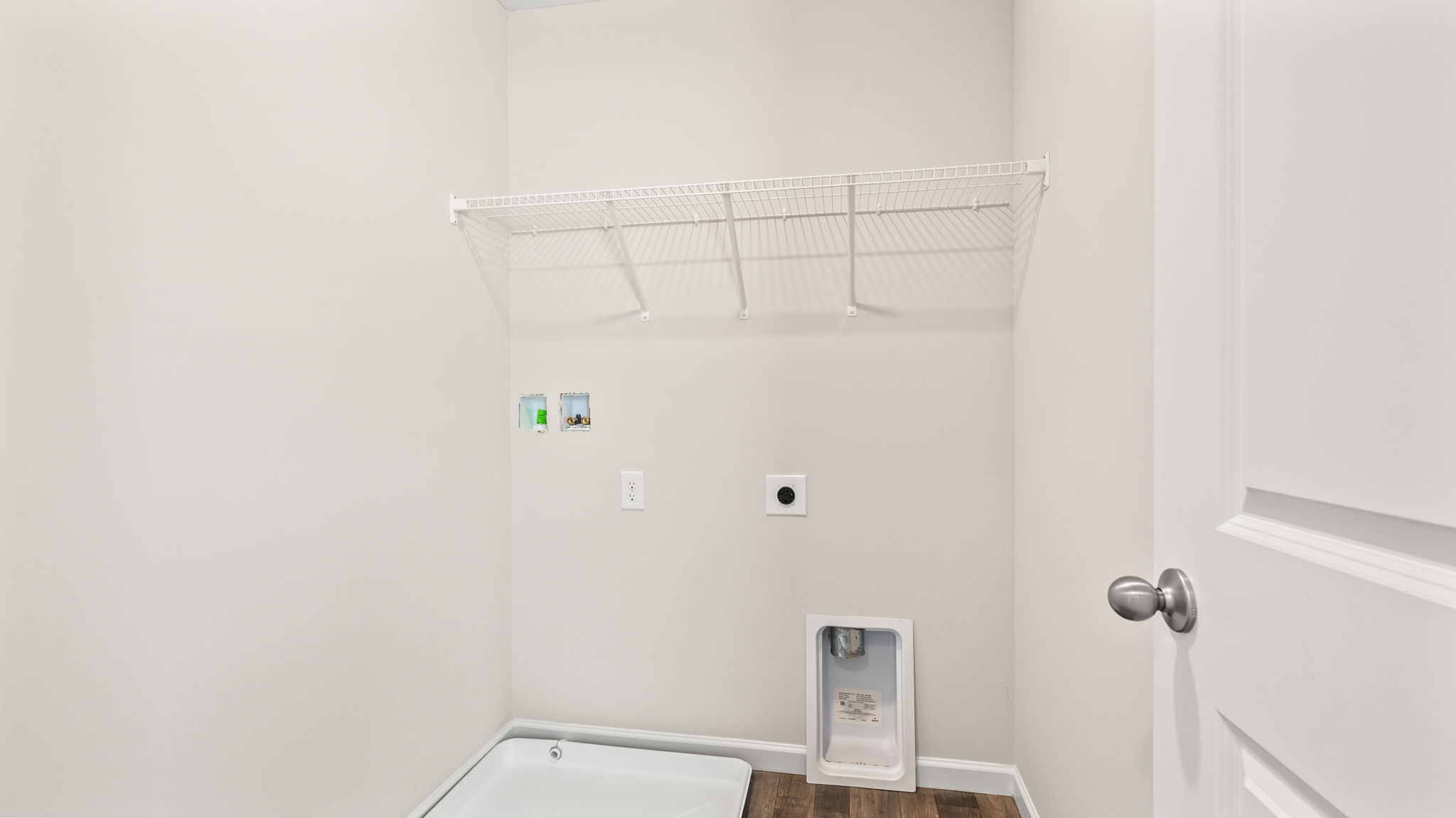 Laundry area with wire rack shelving and washer/dryer inlets