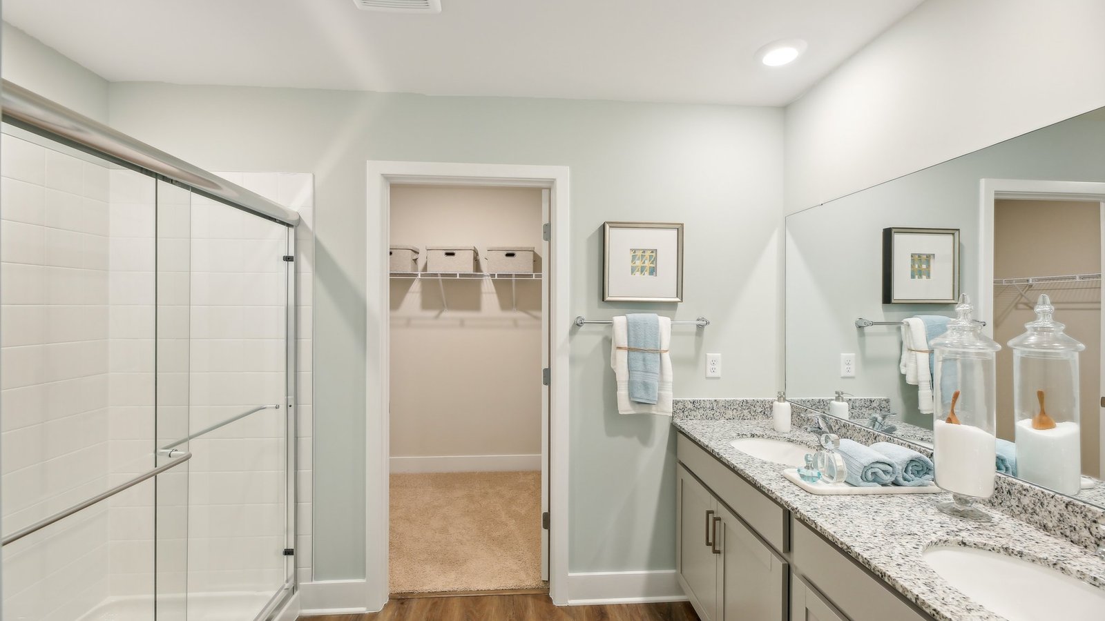 Primary bathroom with granite dual vanity with view to walkin closet.