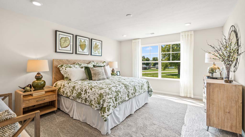 Primary bedroom with green décor and large bed with wooden accents.
