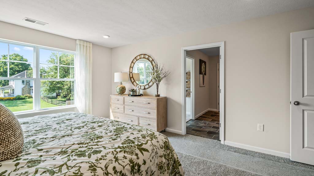 Primary bedroom with green décor and view into the bathroom.