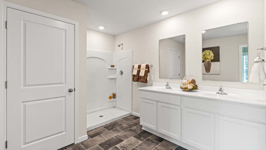 Private bathroom with dual vanity sinks and mirror with white cabinets.