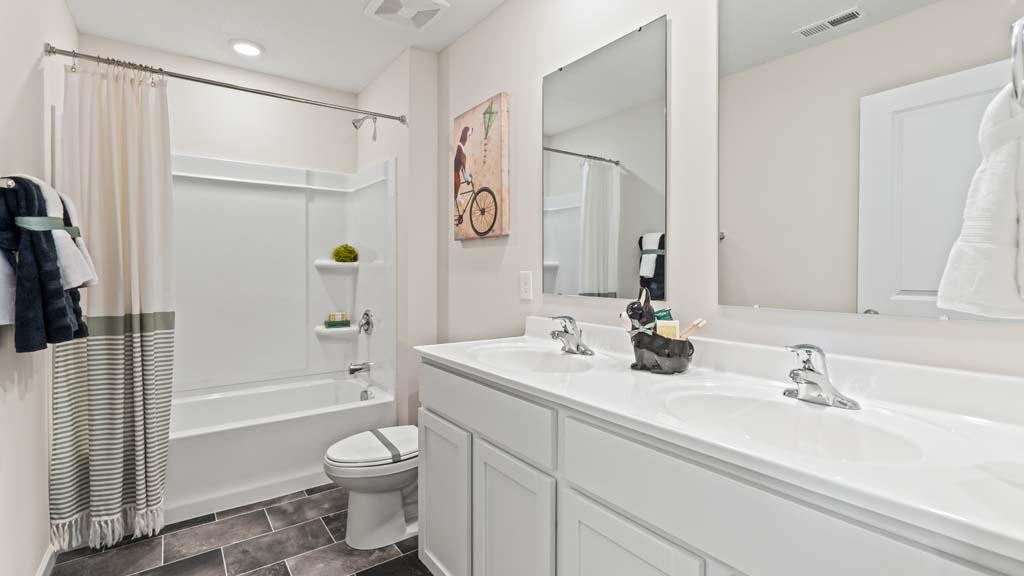 Shared bathroom with dual vanity sinks and shower and toilet with modern décor.