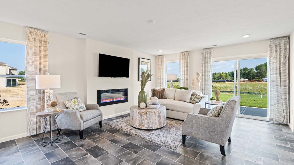 View of the living room with comfy couches, electric fireplace, and view of backyard.