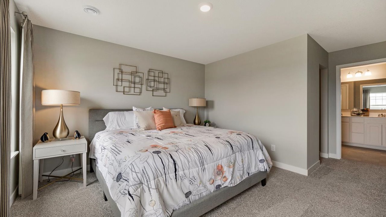 Primary bedroom with large bed, matching bedside tables, and view of the private bathroom.