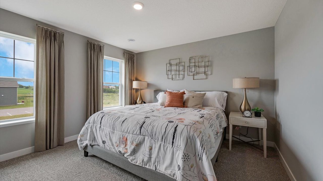Primary bedroom with large bed, matching bedside tables, and views of the outside.