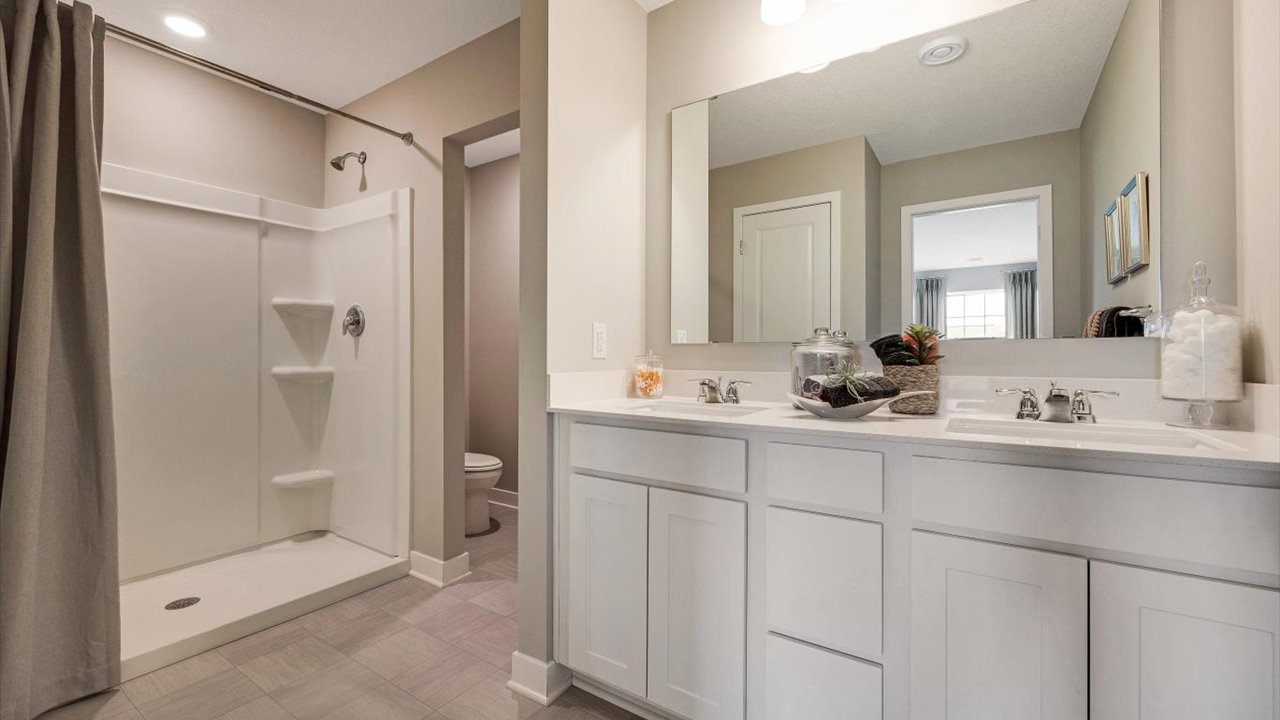 Private bathroom with white countertops on dual vanity sinks, private toilet room, and shower.