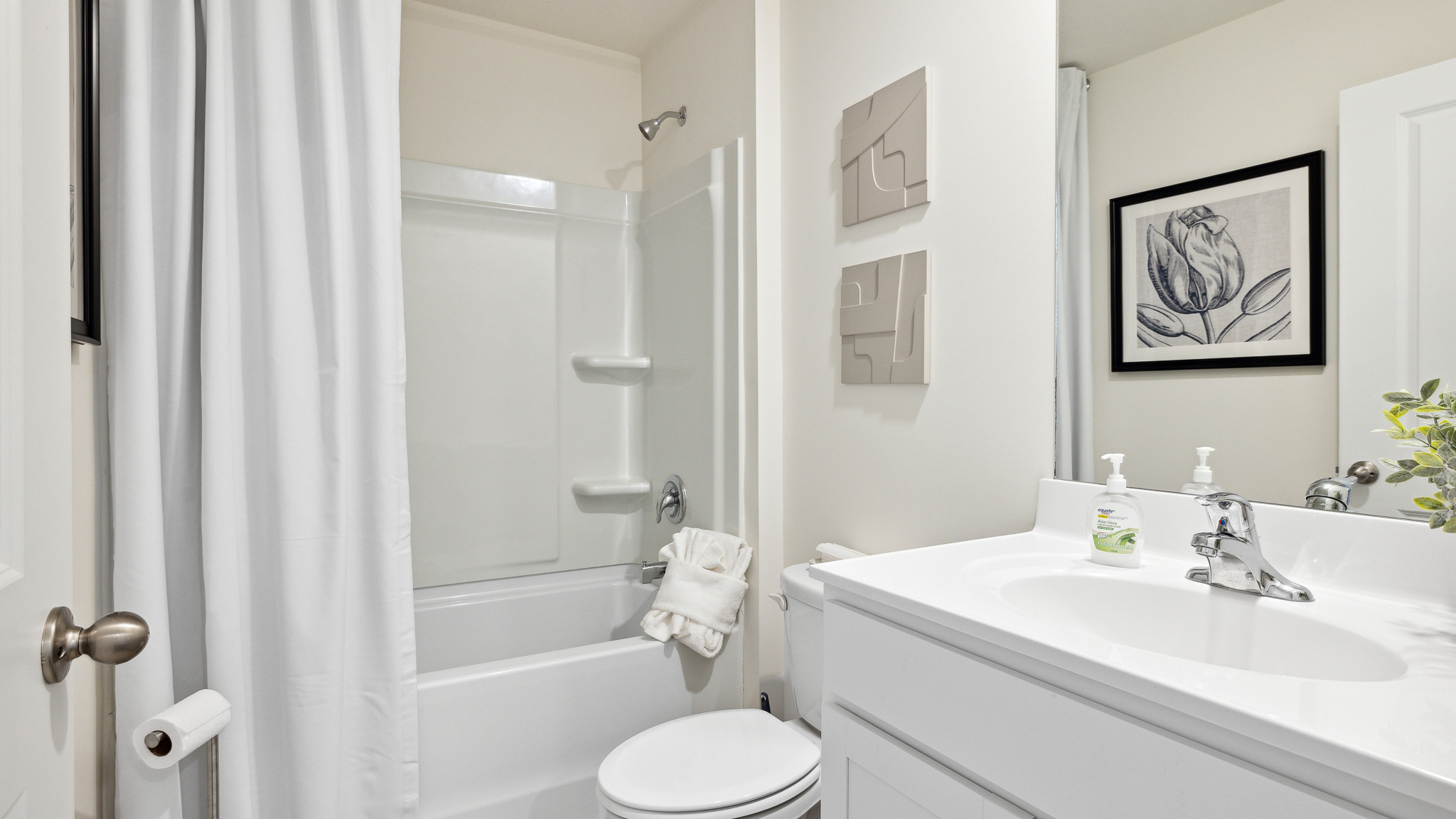 Bathroom with tub/shower, toilet, and vanity with mirror.