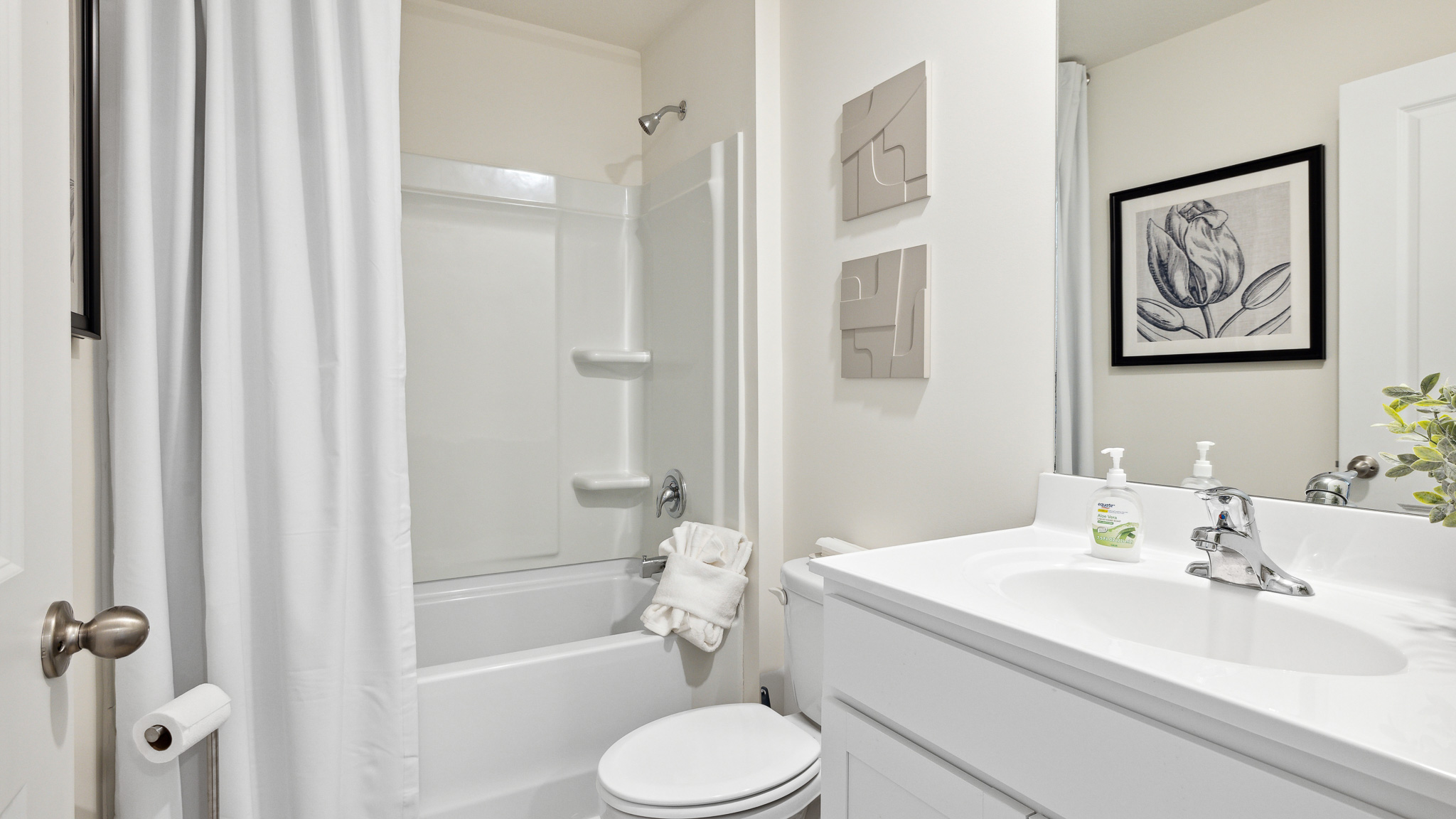 Bathroom with tub/shower, toilet, and vanity with mirror.