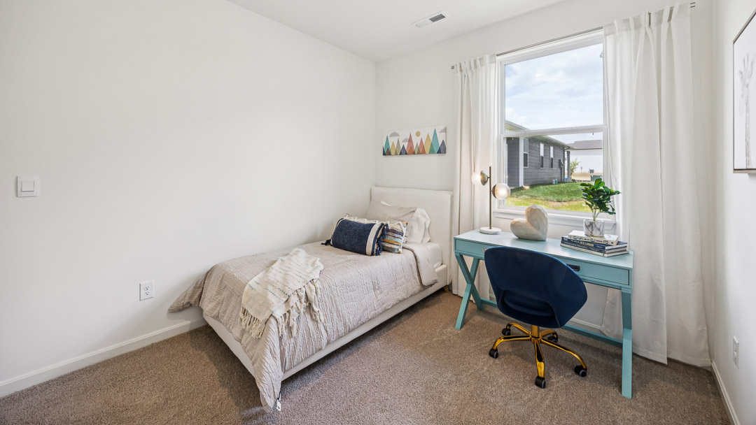 Bedroom with fullsize bed and turquoise desk adjacent