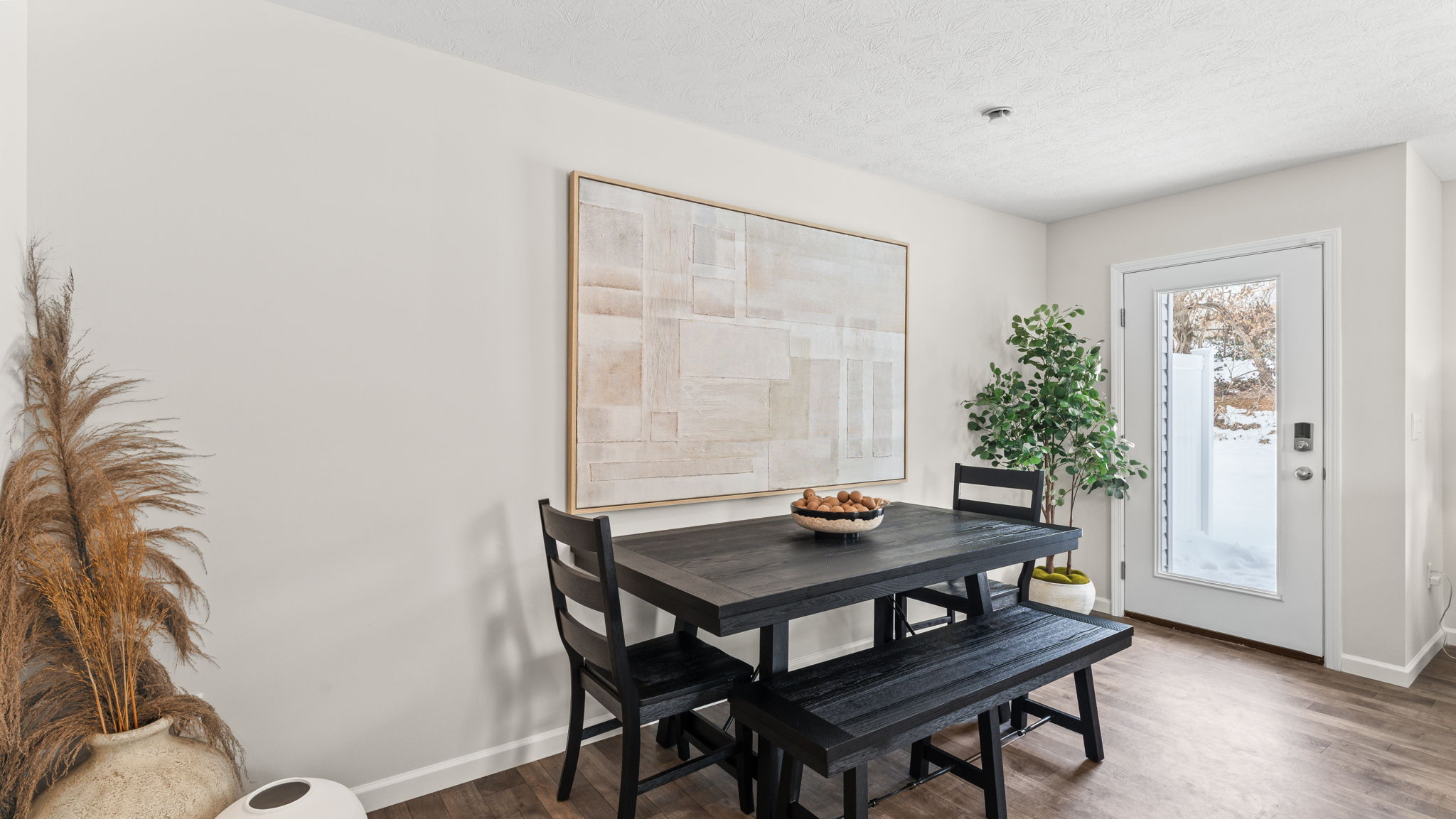 Picnic bench style dining table next to abstract art and plant for decoration