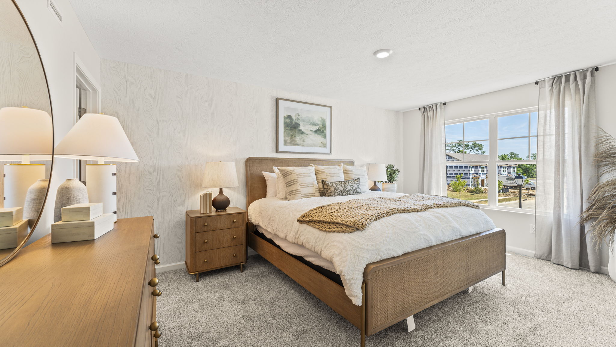 Primary bedroom with light wooden accents and large bed.
