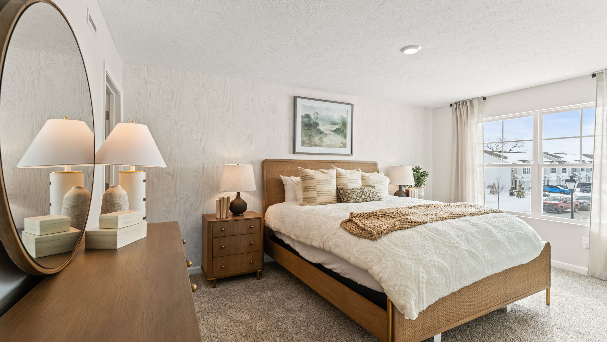 Three-quarter view of primary bedroom with dresser and mirror on the left