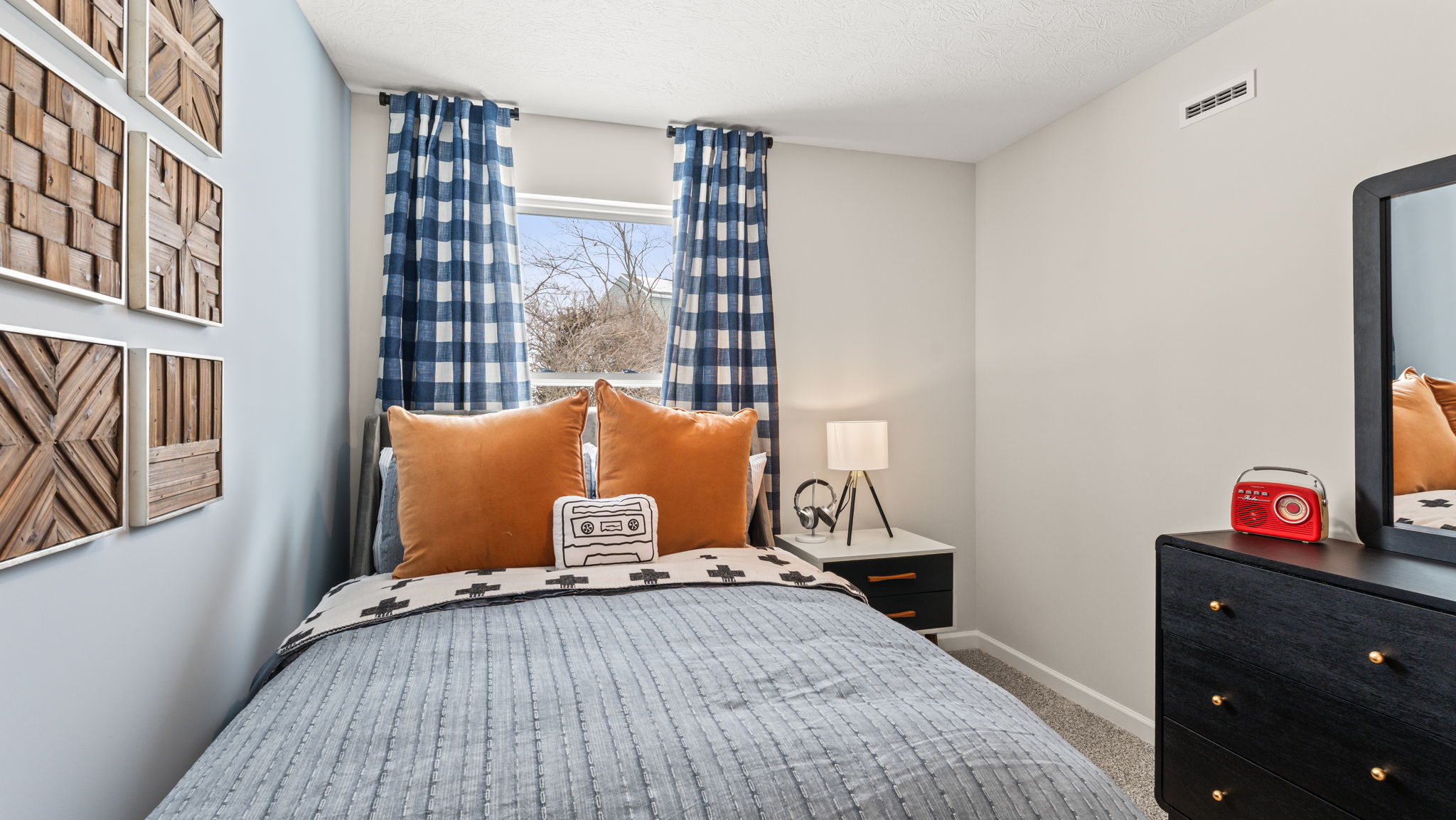 Closeup of full-sized bed with blue comforter and orange pillows