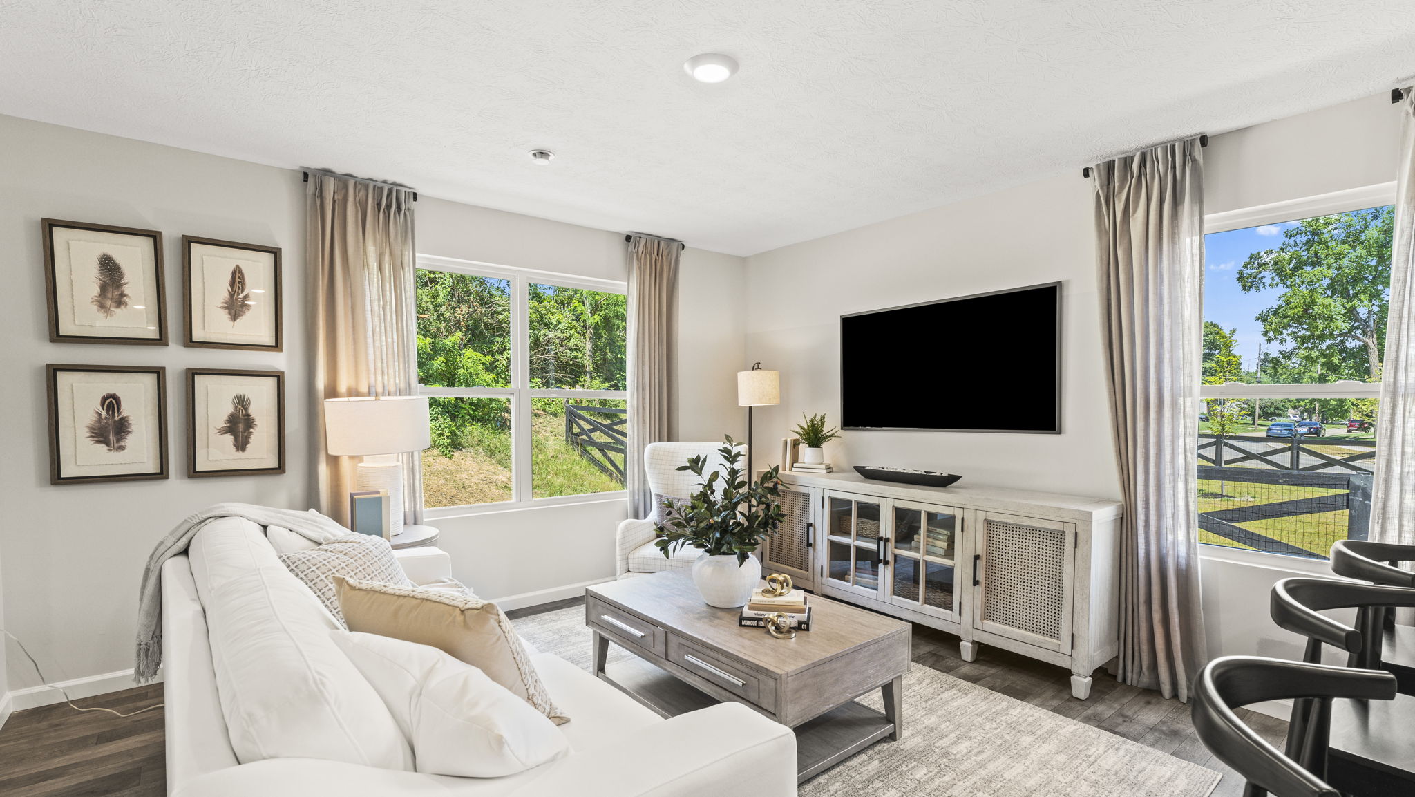 Spacious great room with a gorgeous white couch, dark hardwood dining room, and kitchen with stainless steel appliances and white cabinetry.