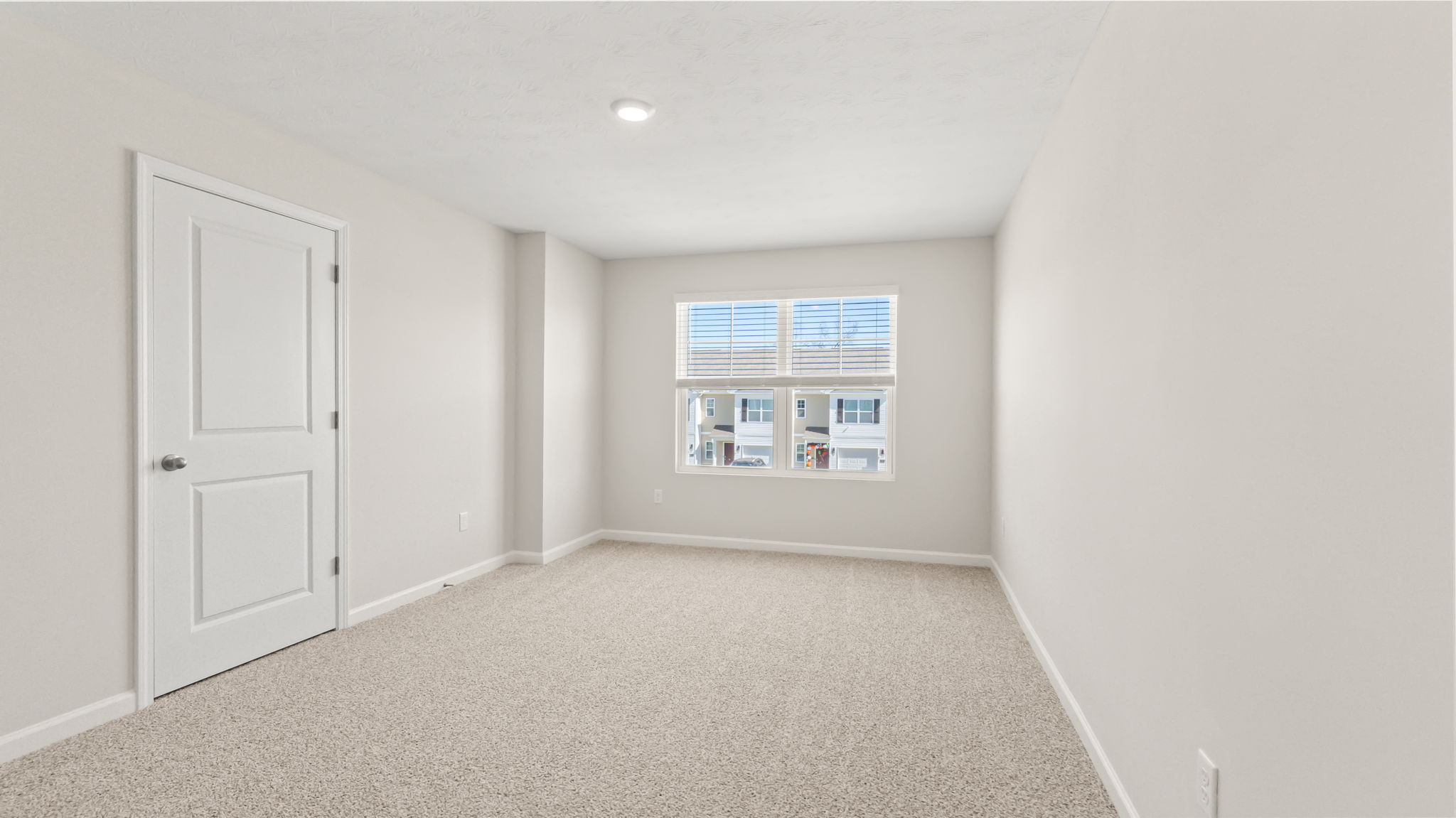 Carpeted primary bedroom with window