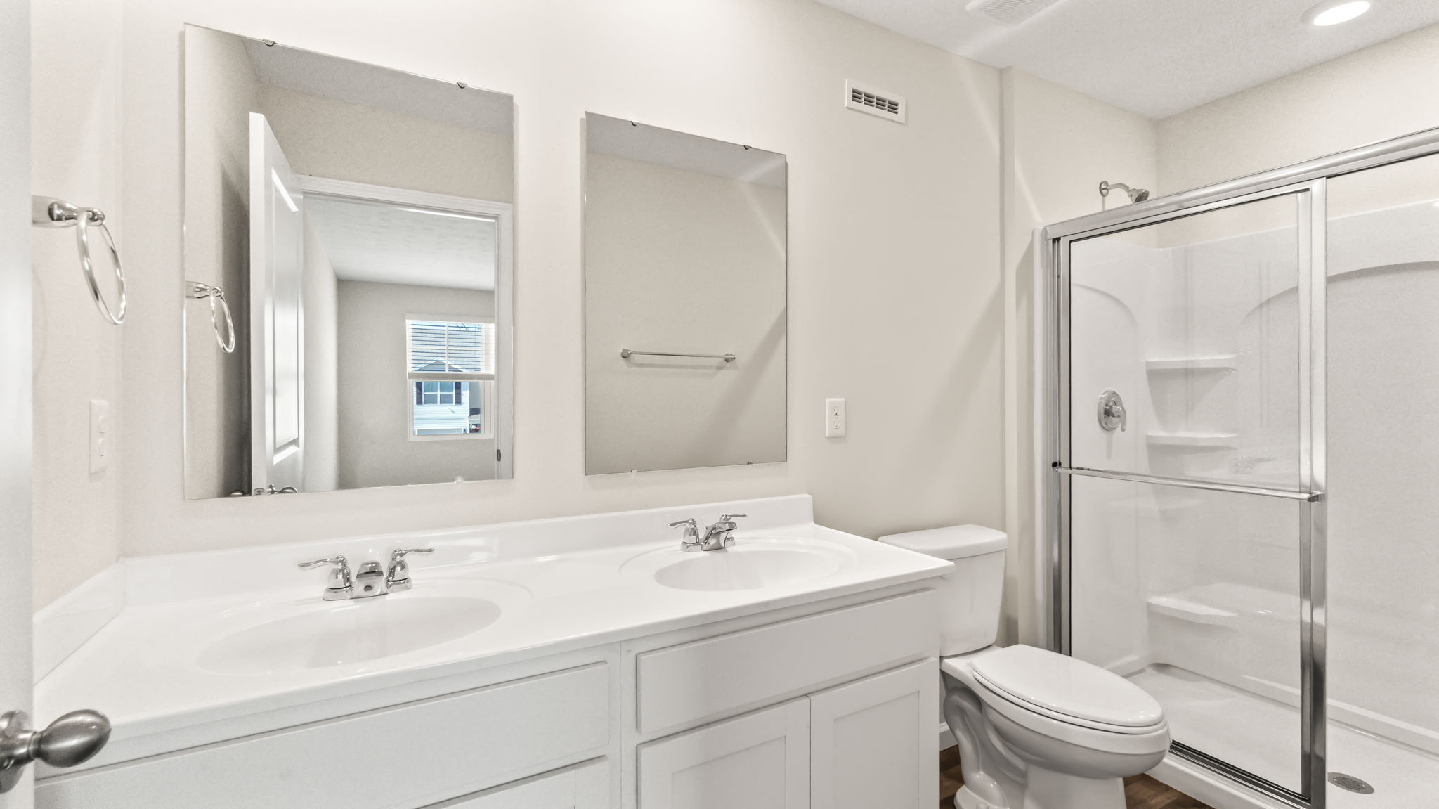 primary bathroom suite with dual sink vanities and shower with sliding glass door