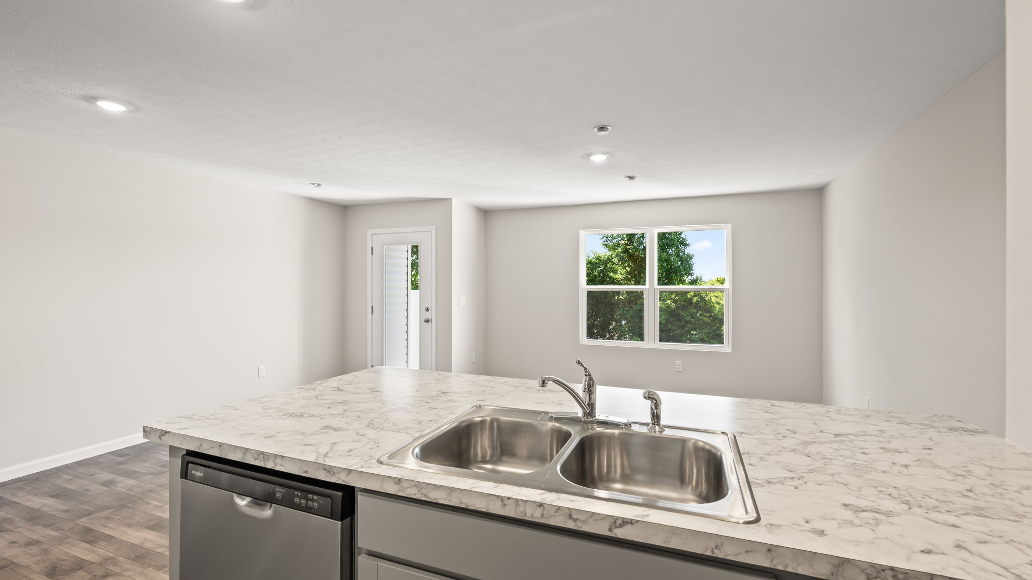 Perspective image from behind kitchen peninsula with sink and dishwasher