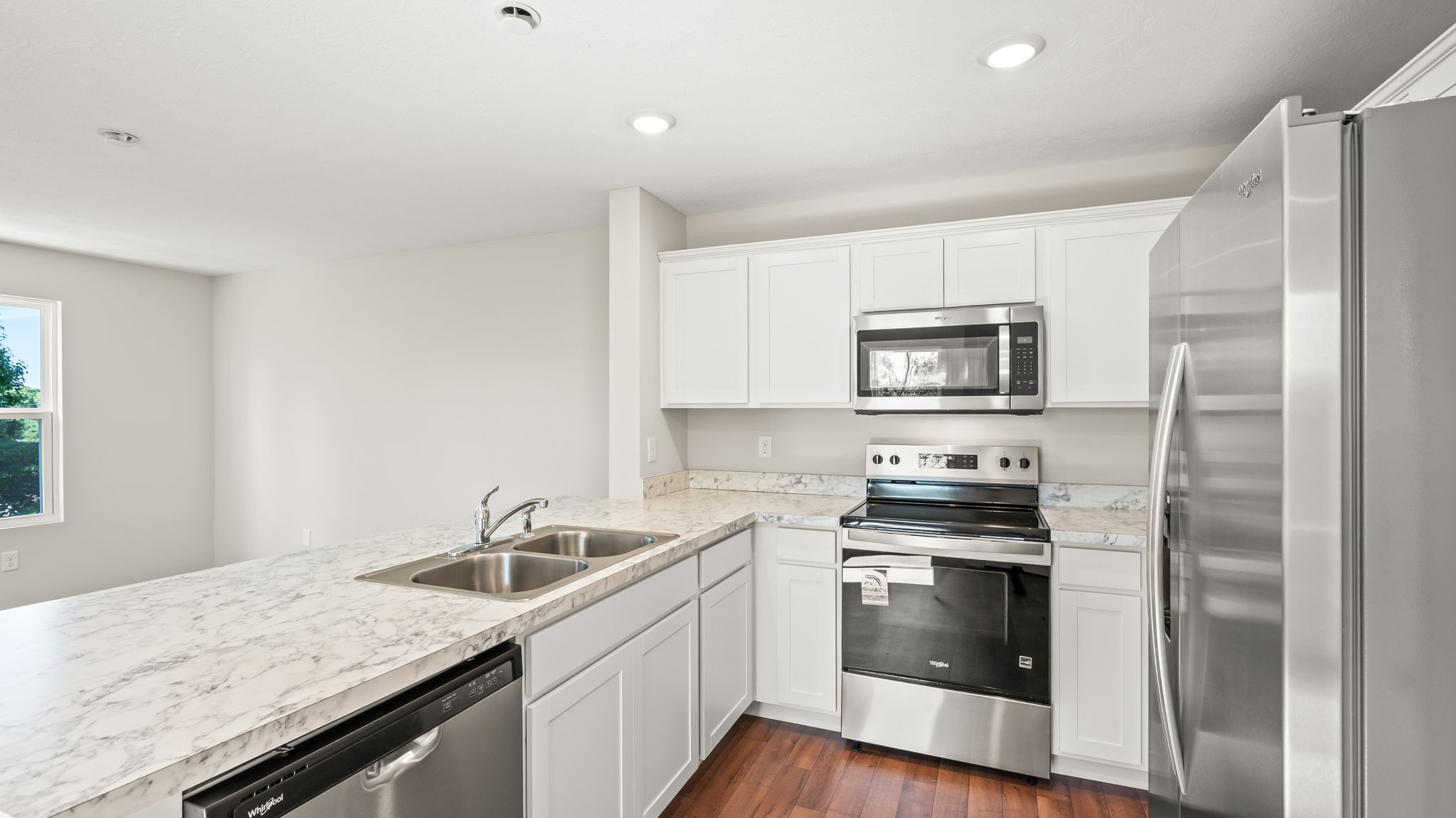 full kitchen from side view with appliances including dishwasher, oven, and microwave.
