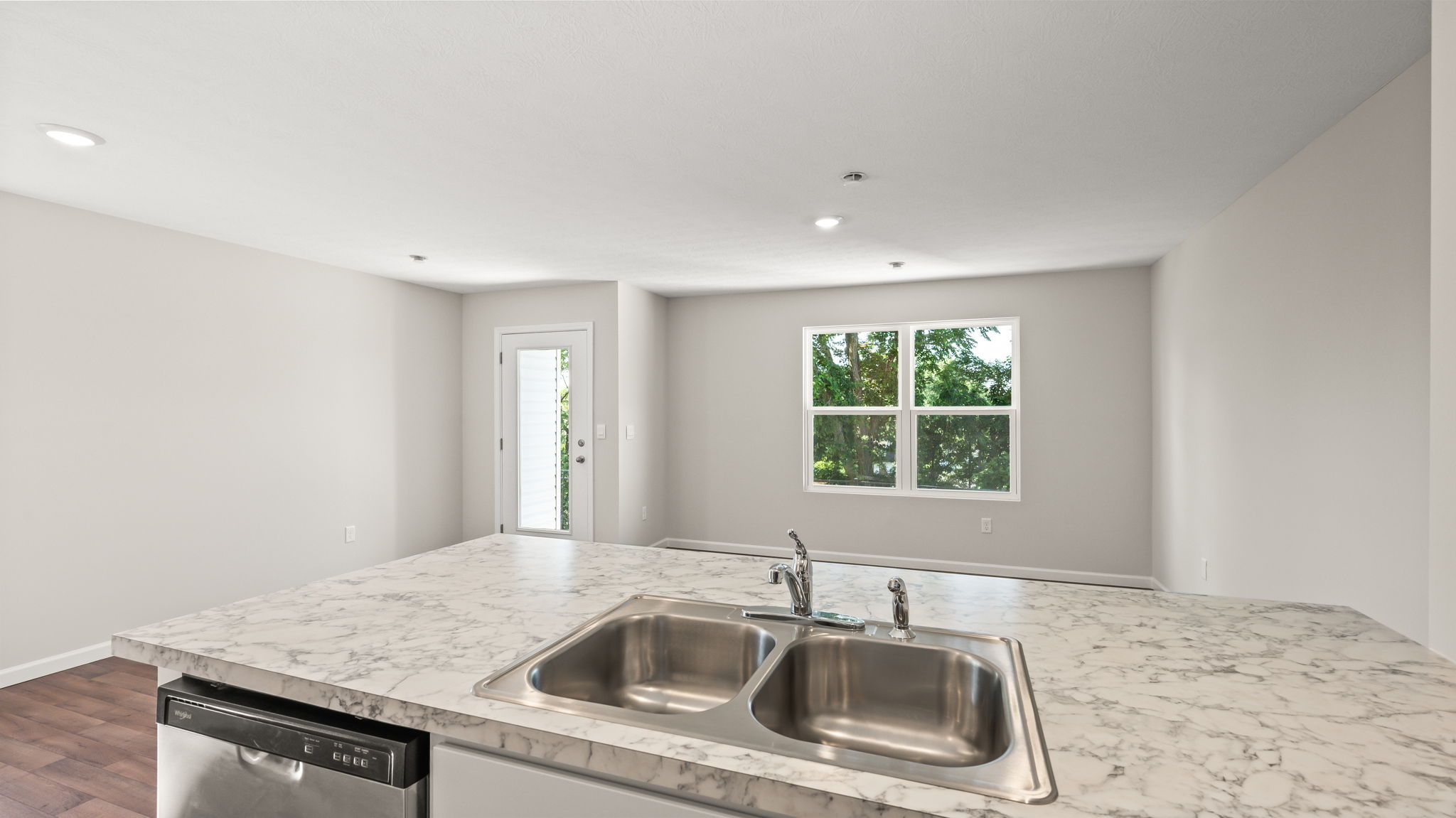 Perspective image from behind kitchen peninsula with sink and dishwasher