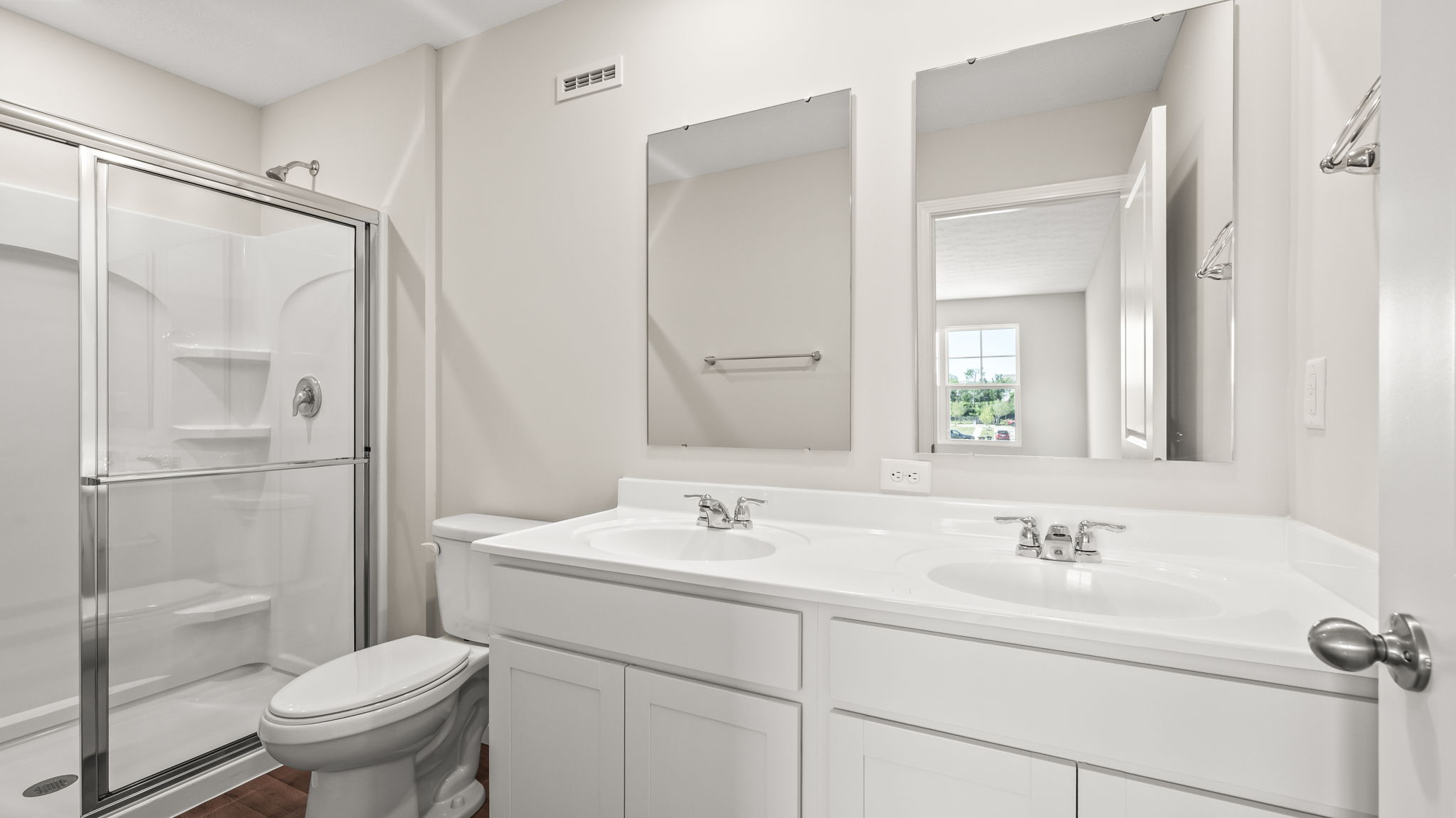 Primary bathroom suite with sliding glass door, toilet, and double sink vanity with mirrors