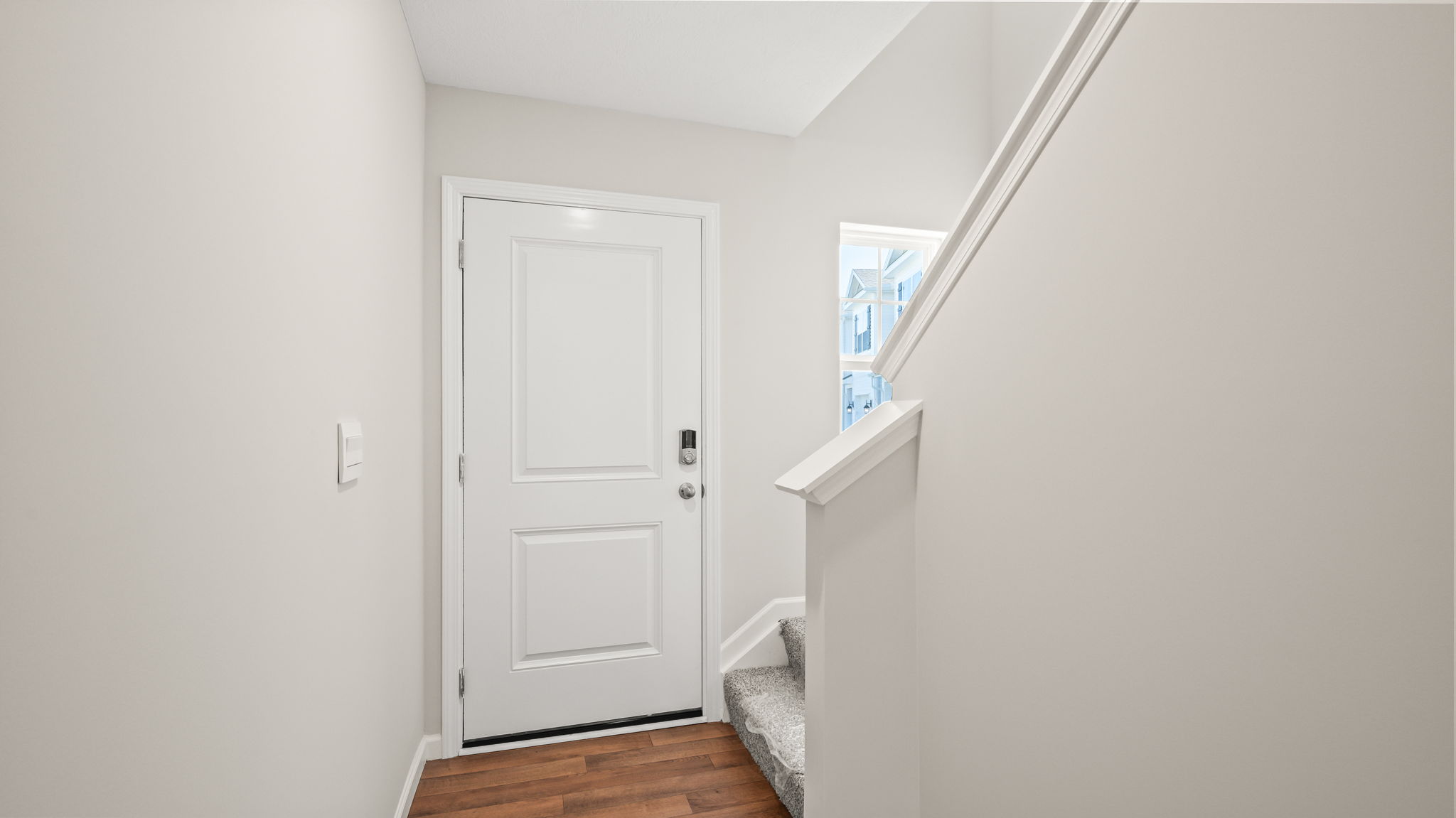 Foyer of townhome leading to front door and stairs to second floor