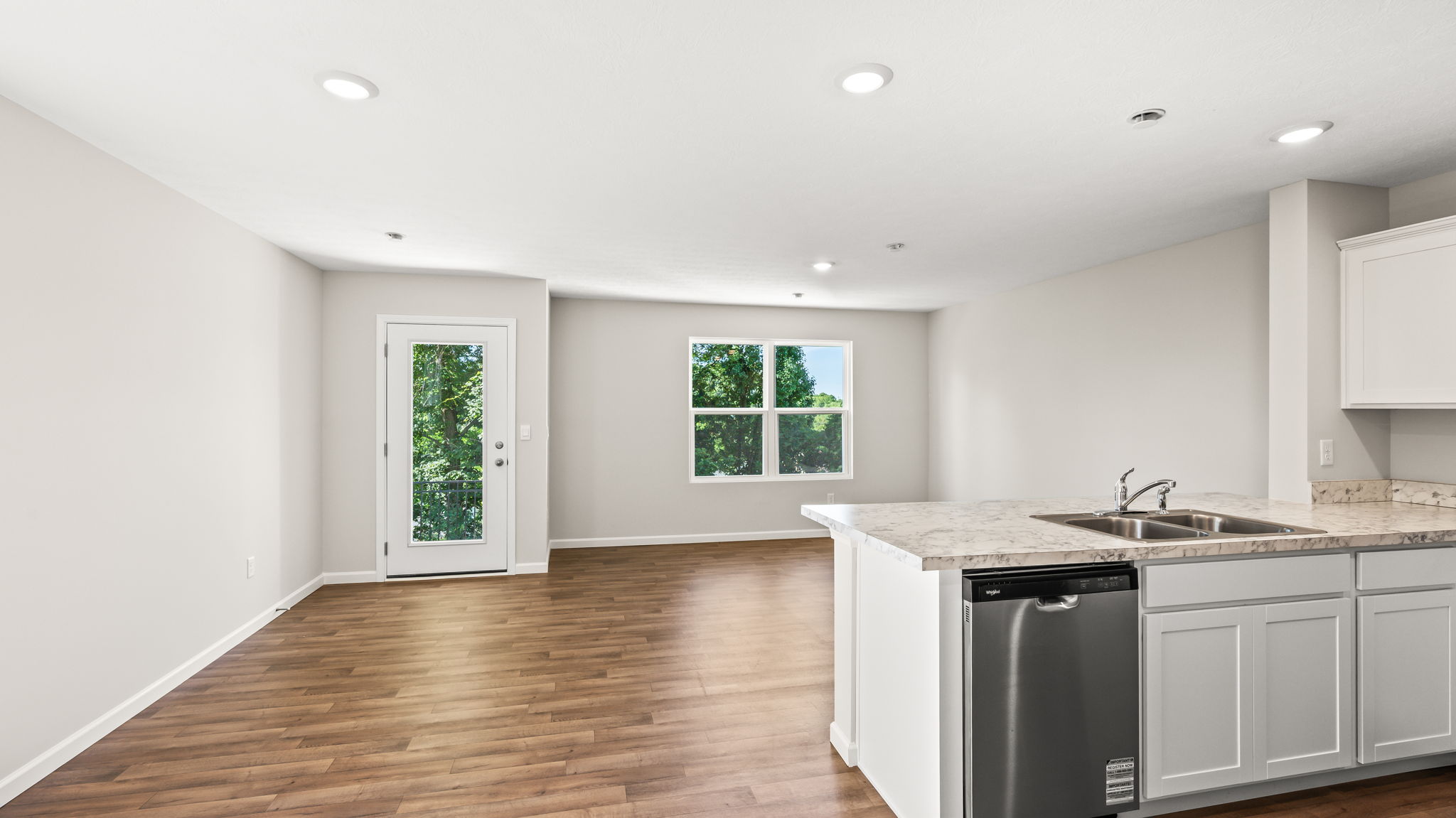 Perspective image from behind kitchen peninsula with sink and dishwasher