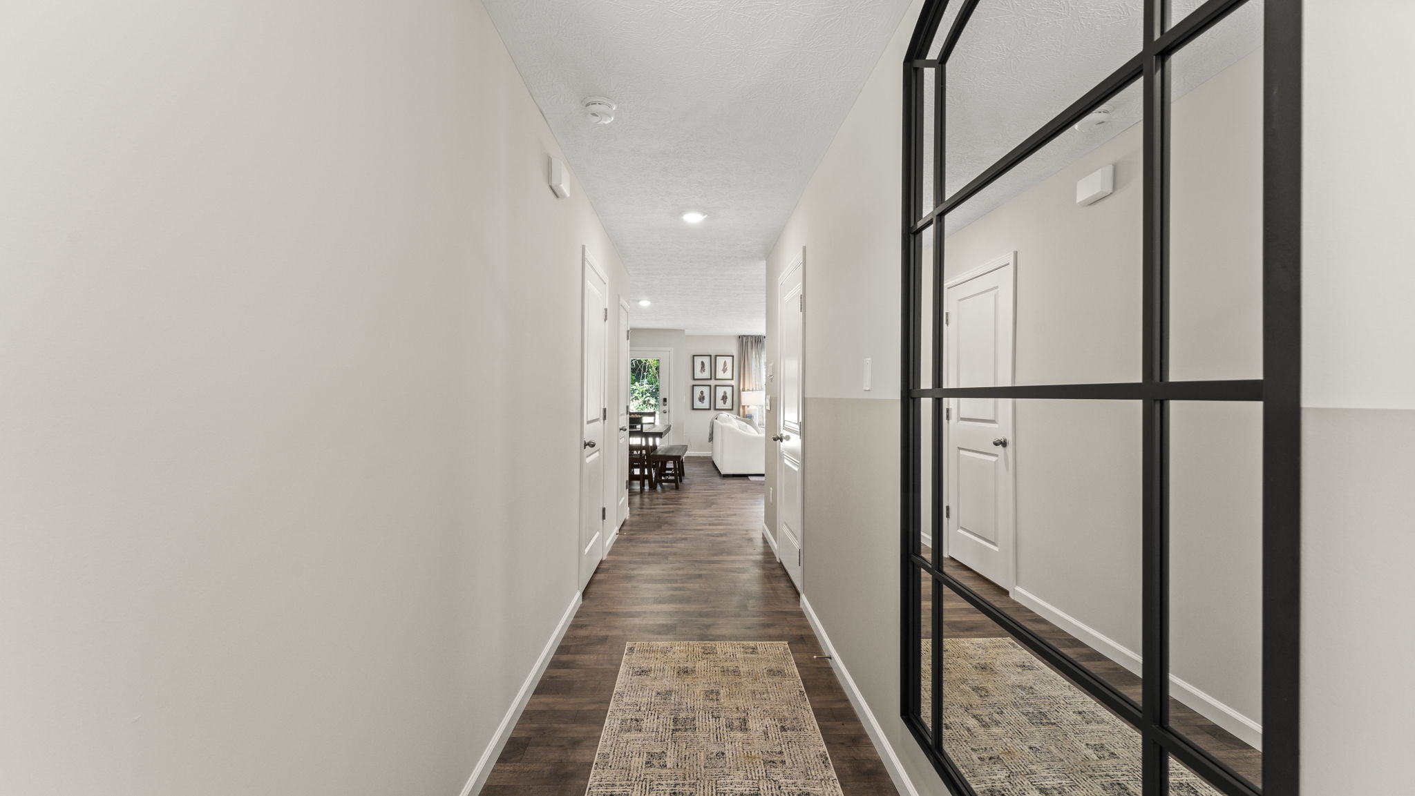View of hallway into living room and large black mirror.