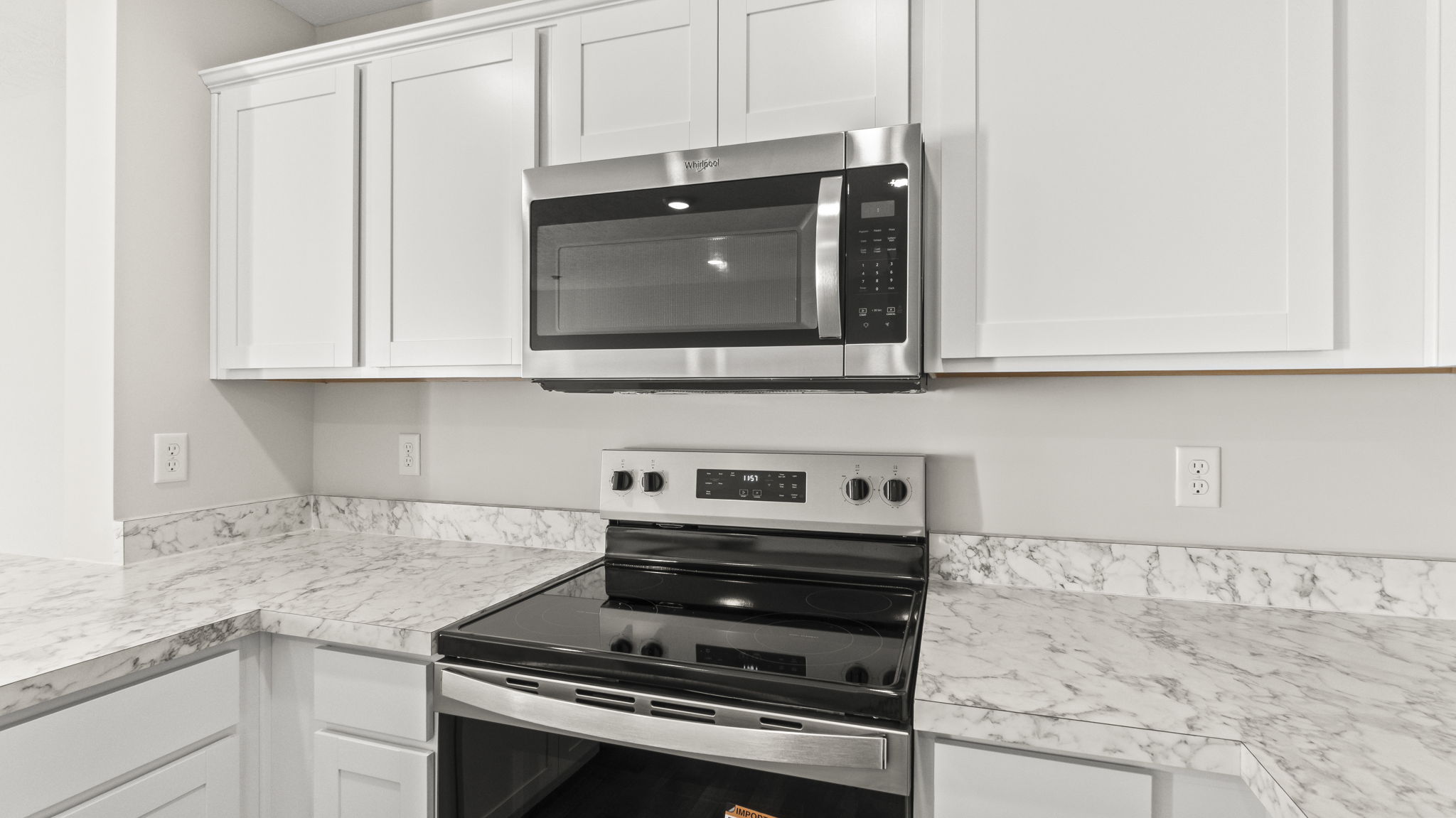 Cloesup of stove and microwave between laminate countertops and white cabinets respectively.