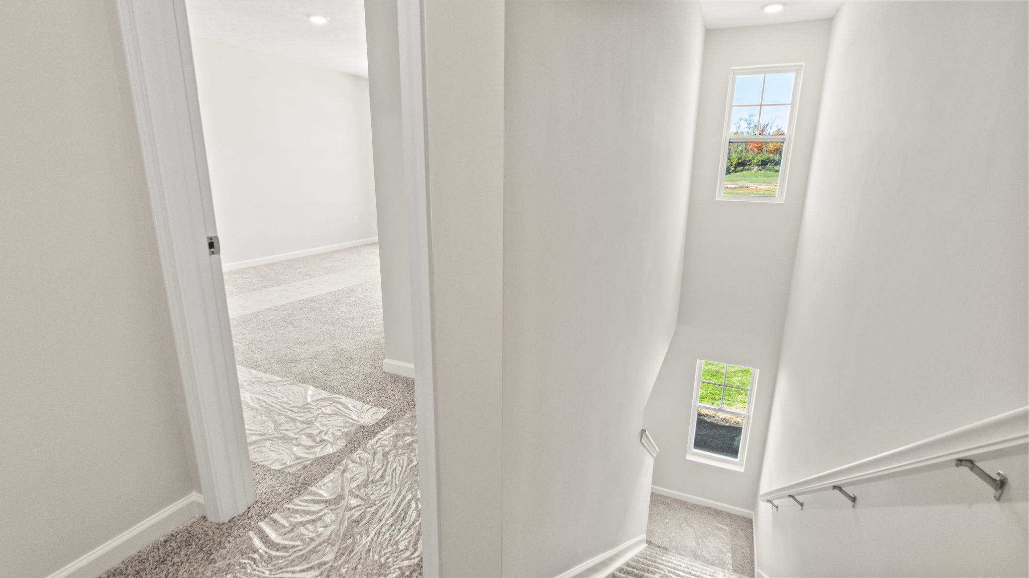Upstais looking down at carpeted stairs and into carpeted primary bedroom