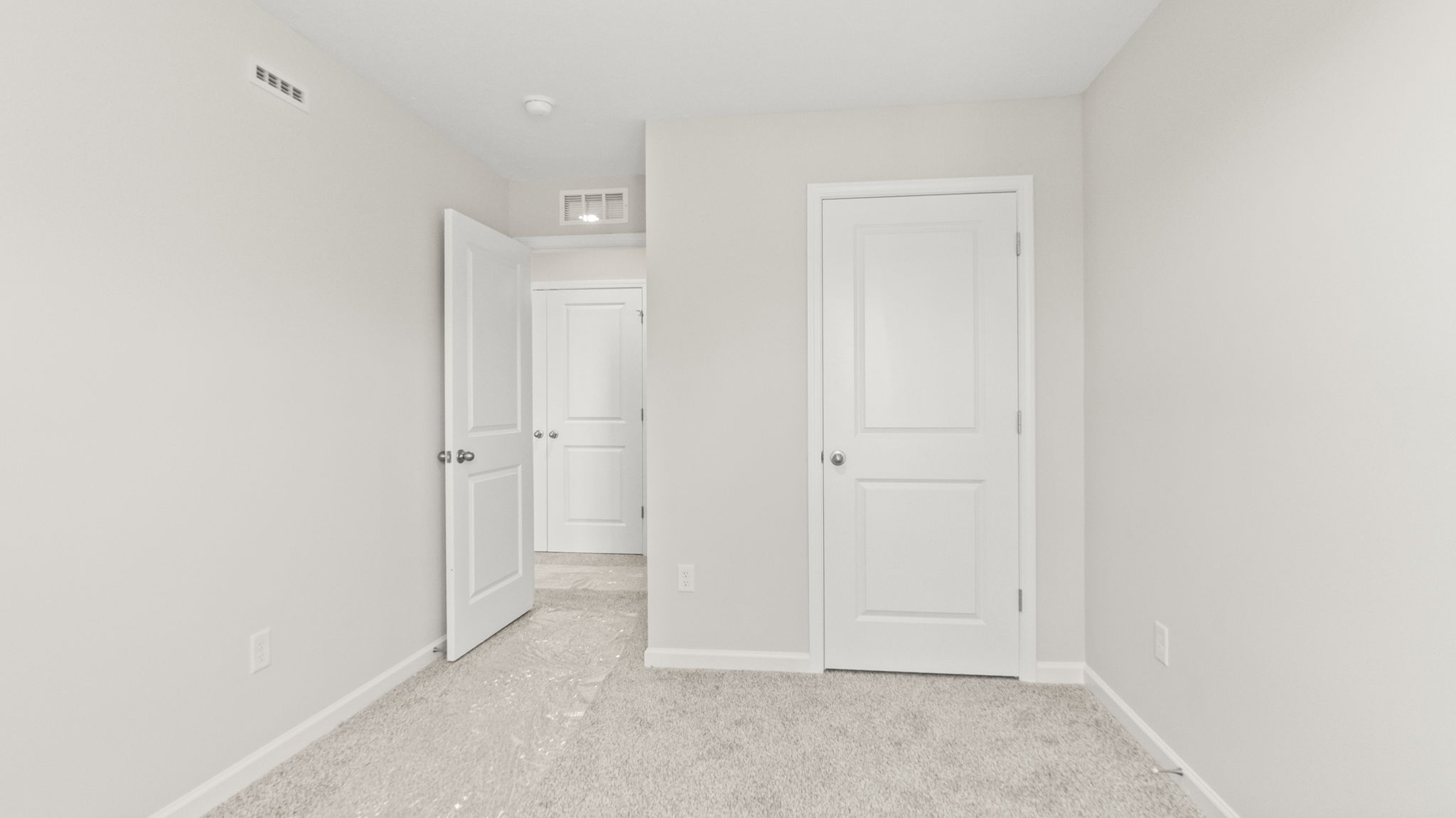 Carpeted bedroom with outlet, door to hallway, and closet.