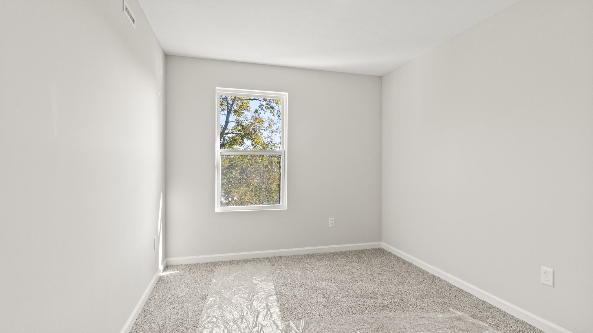 Carpeted bedroom with outlets and window.