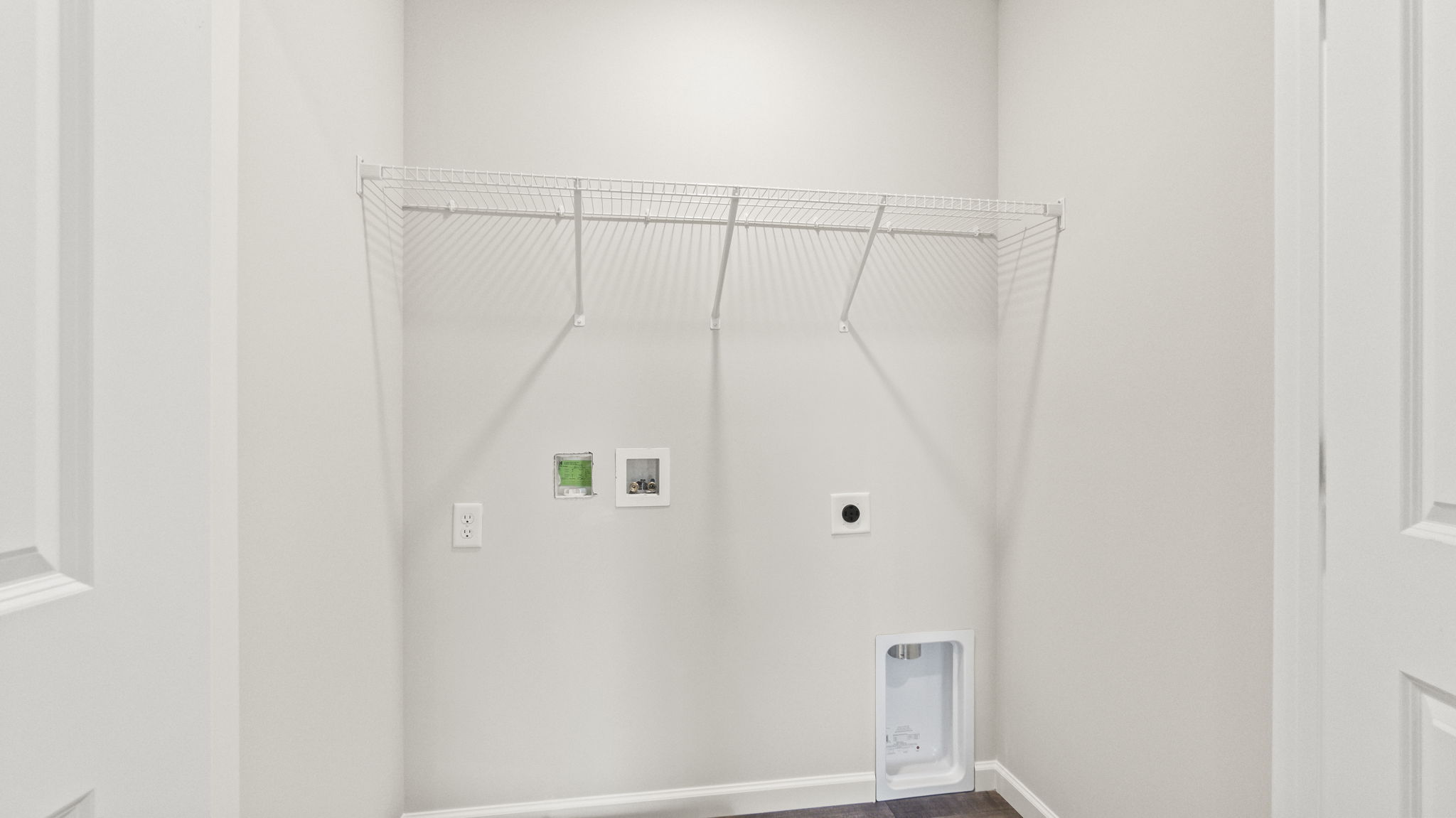 Laundry area with wire shelving and washer/dryer inlets.