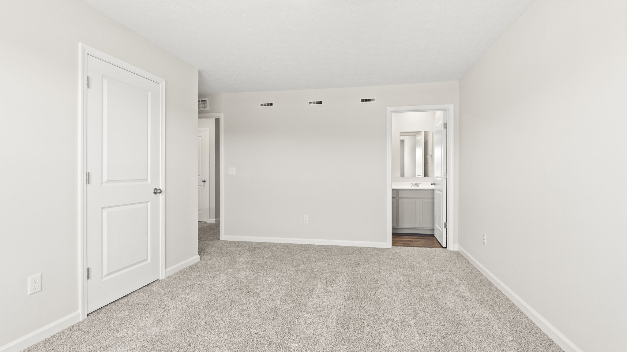 Primary bedroom with door to walk-in closet and primary bathroom