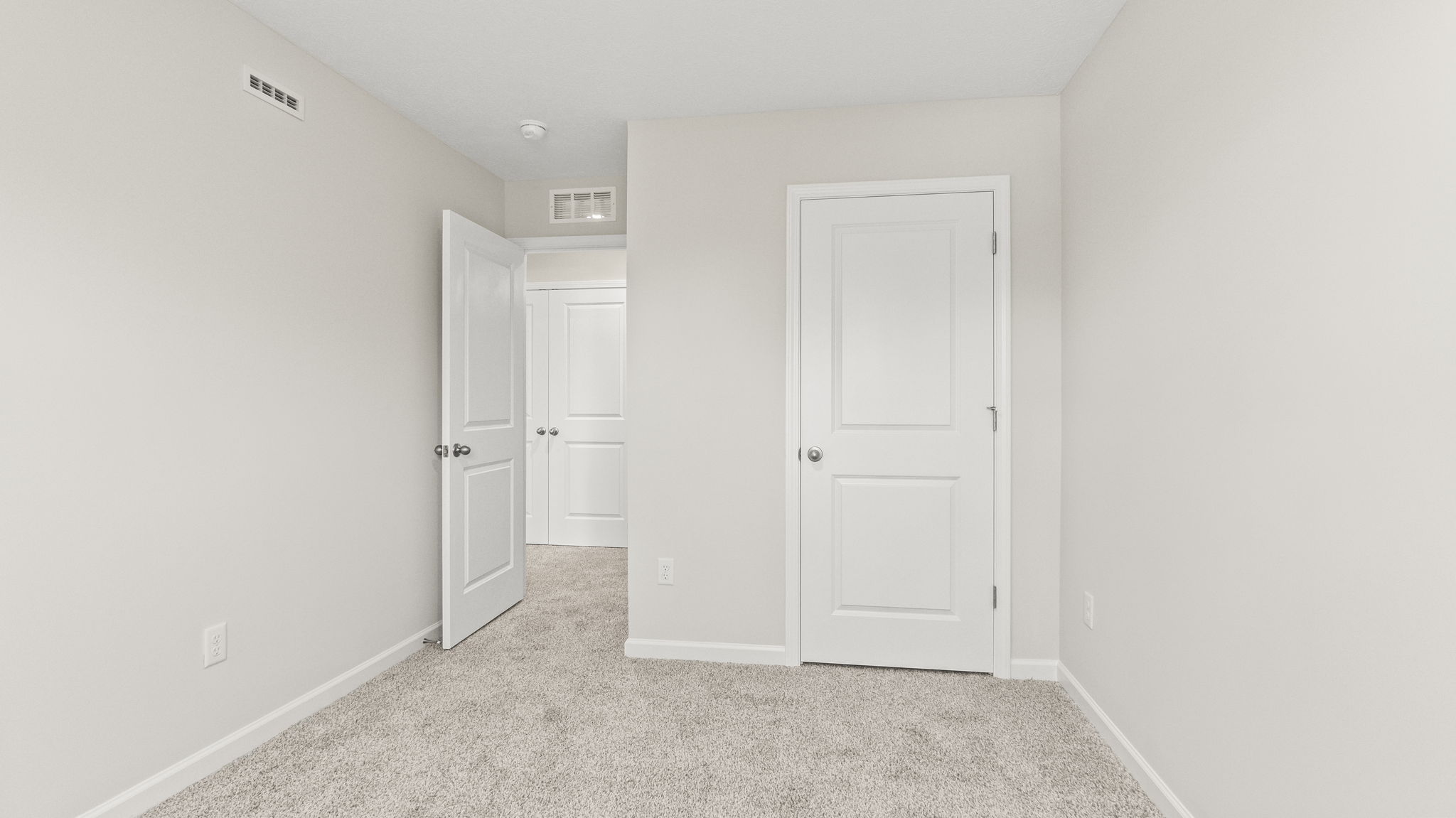 Carpeted bedroom with outlet, door to hallway, and closet.
