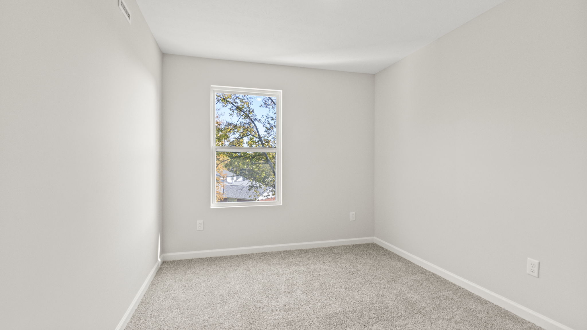 Carpeted bedroom with outlets and window.