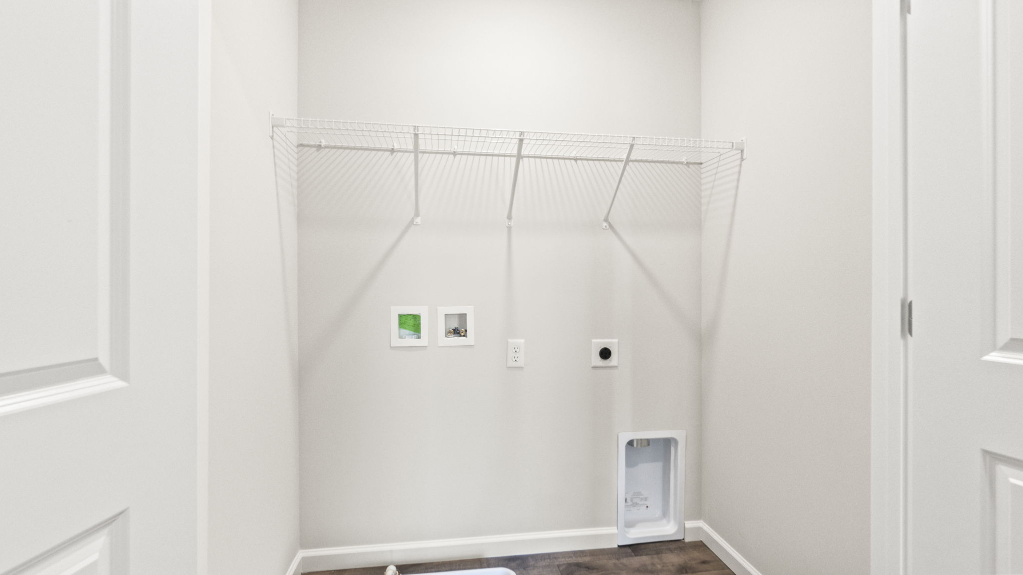 Laundry area with wire shelving and washer/dryer inlets.