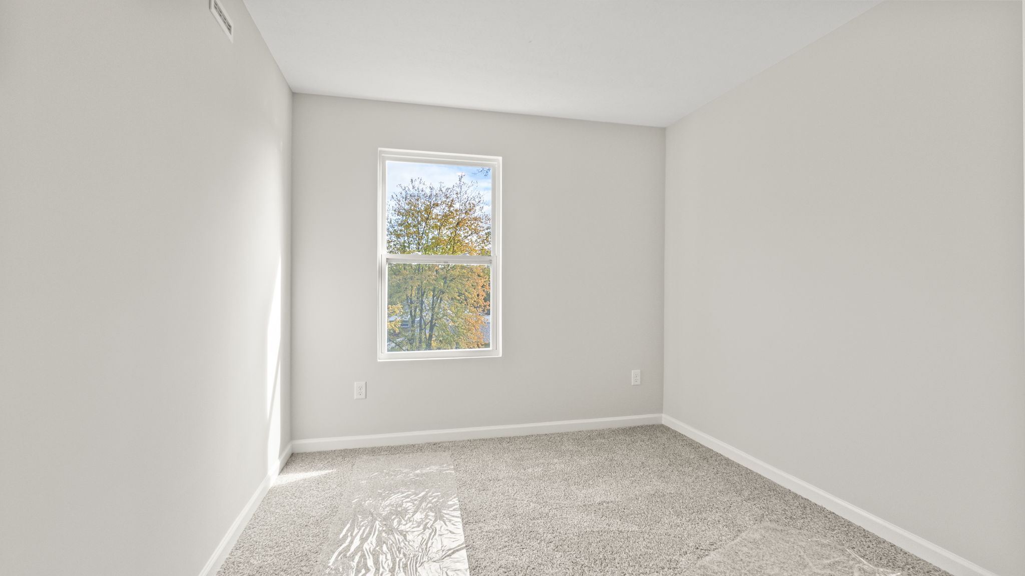 Carpeted bedroom with outlets and window.