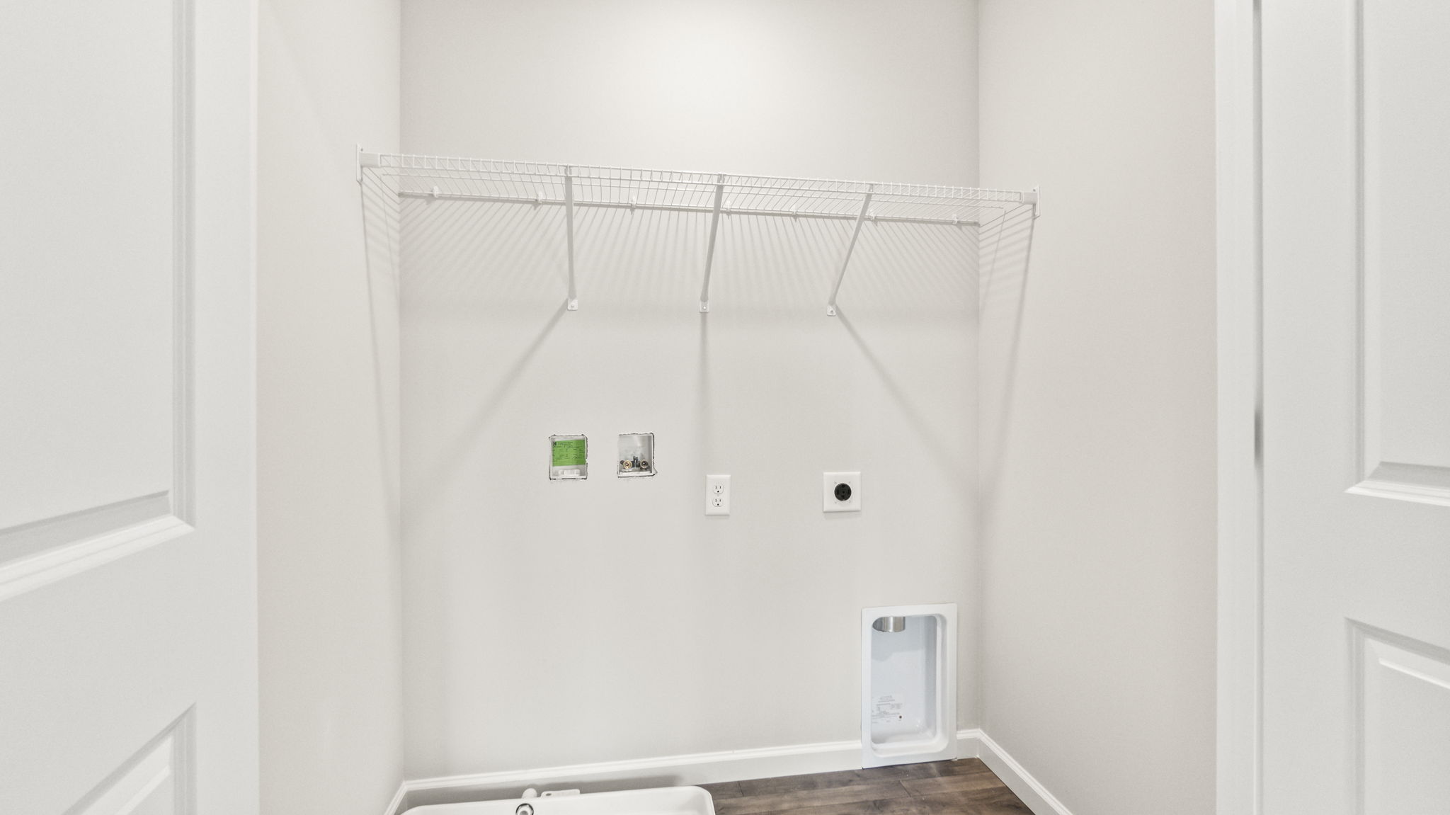 Laundry area with wire shelving and washer/dryer inlets.