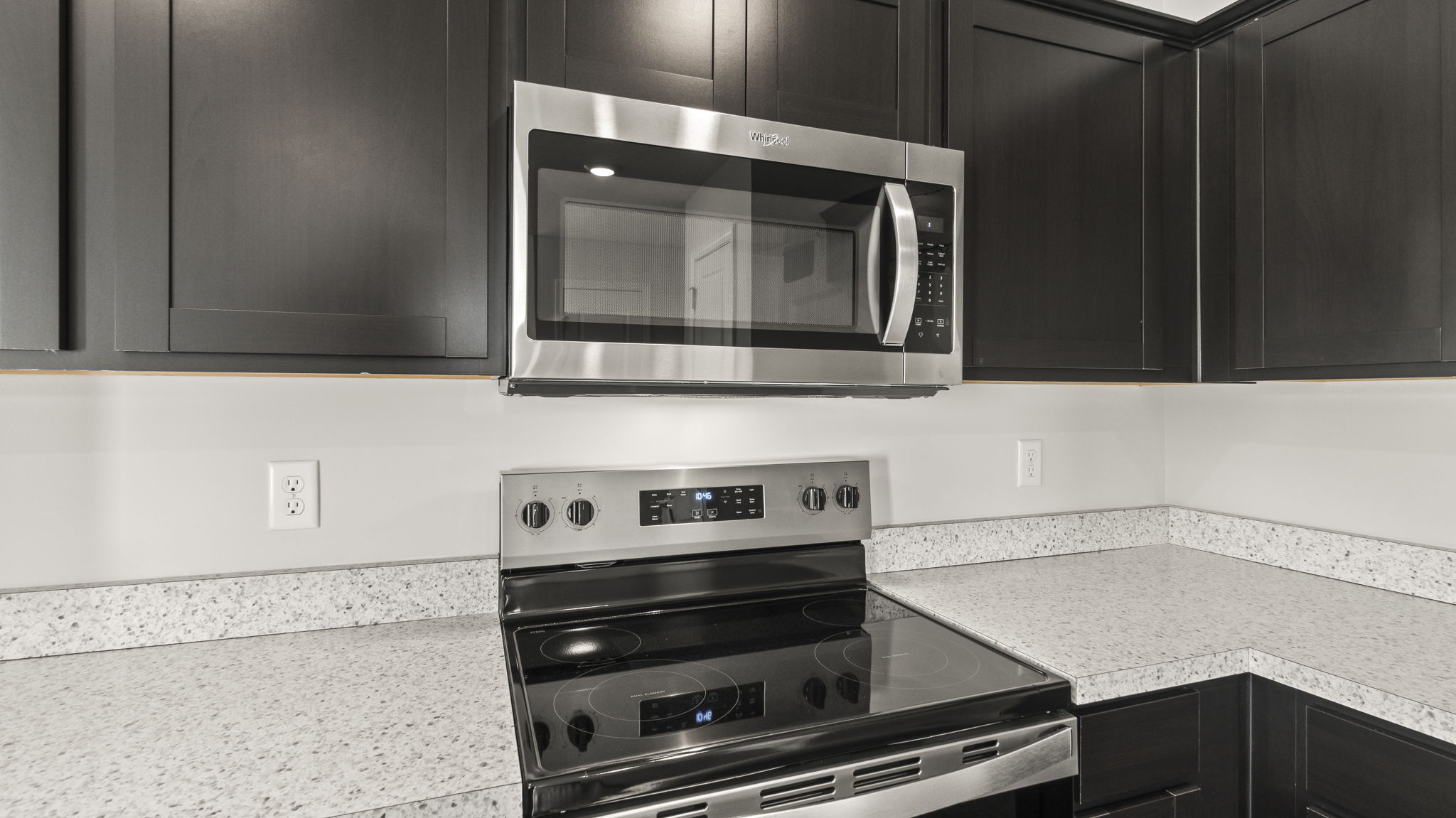 Cloesup of stove and microwave between laminate countertops and woodgrain cabinets respectively.