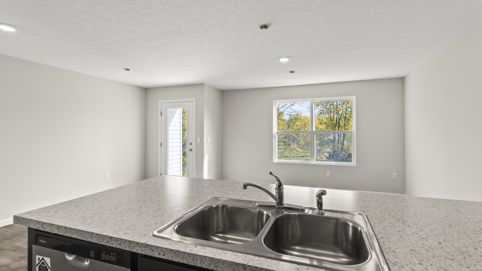 Point of view from the sink into the great area which has the door to the backyard and a window.